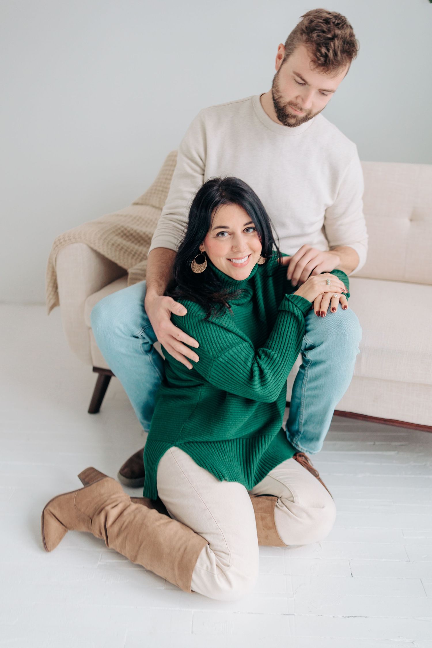 Couple in casual attire sharing intimate moments while sitting on a light colored couch.