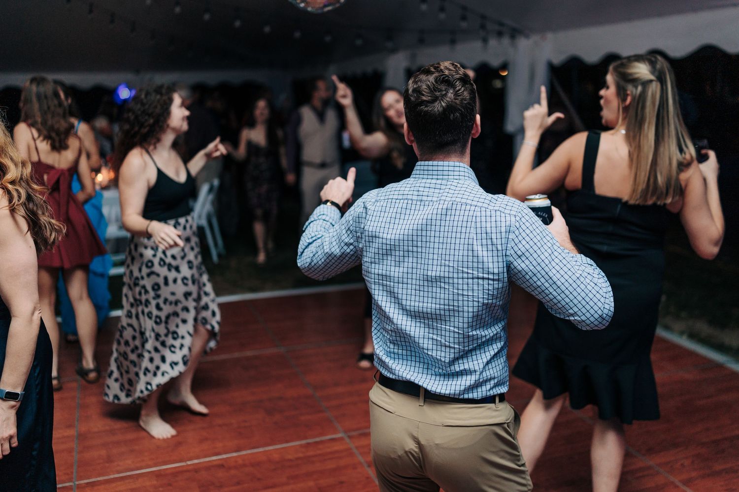 Wedding guests dancing and celebrating on a red dance floor at an indoor reception.