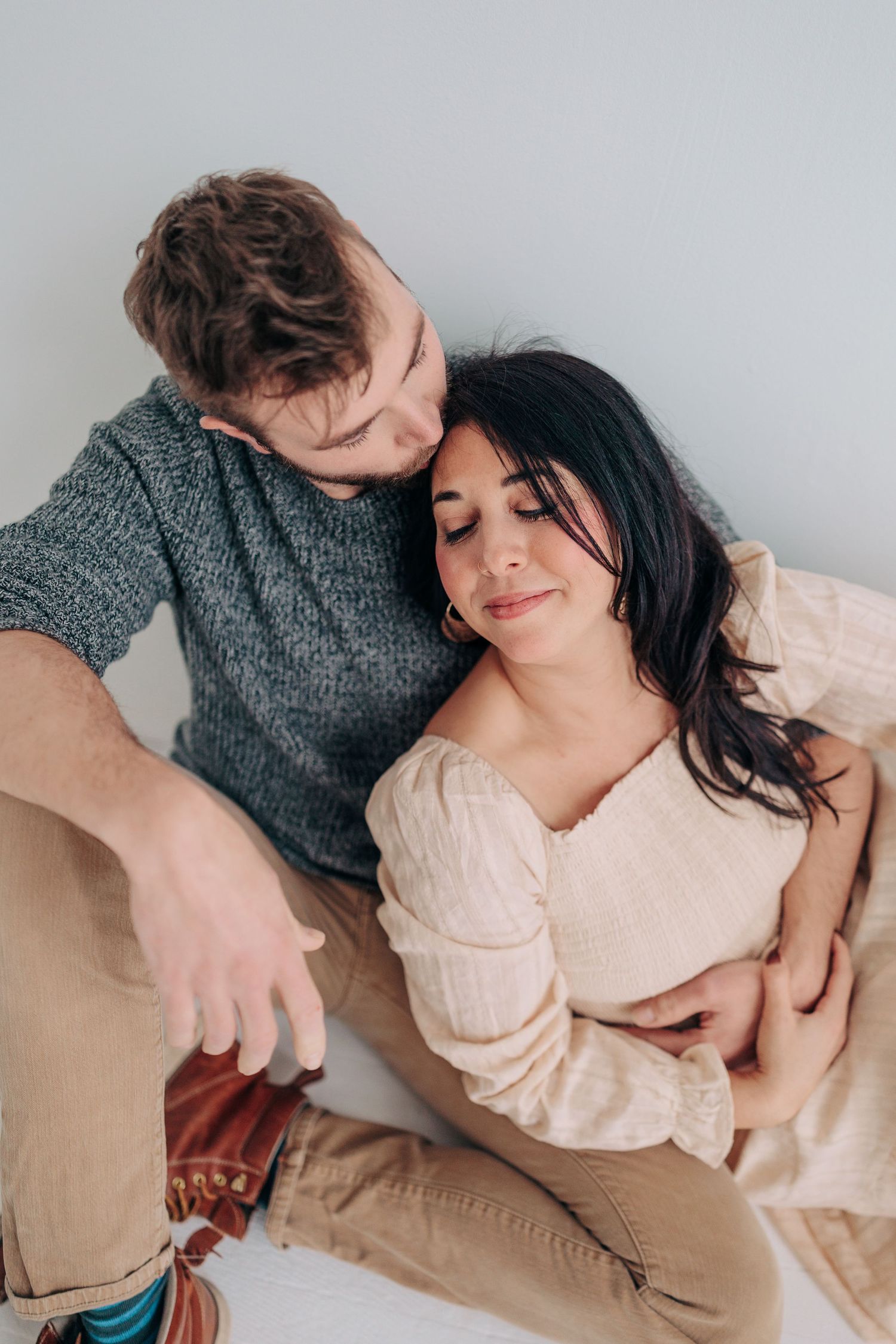 Couple lounging together on floor showing affection in natural light setting.