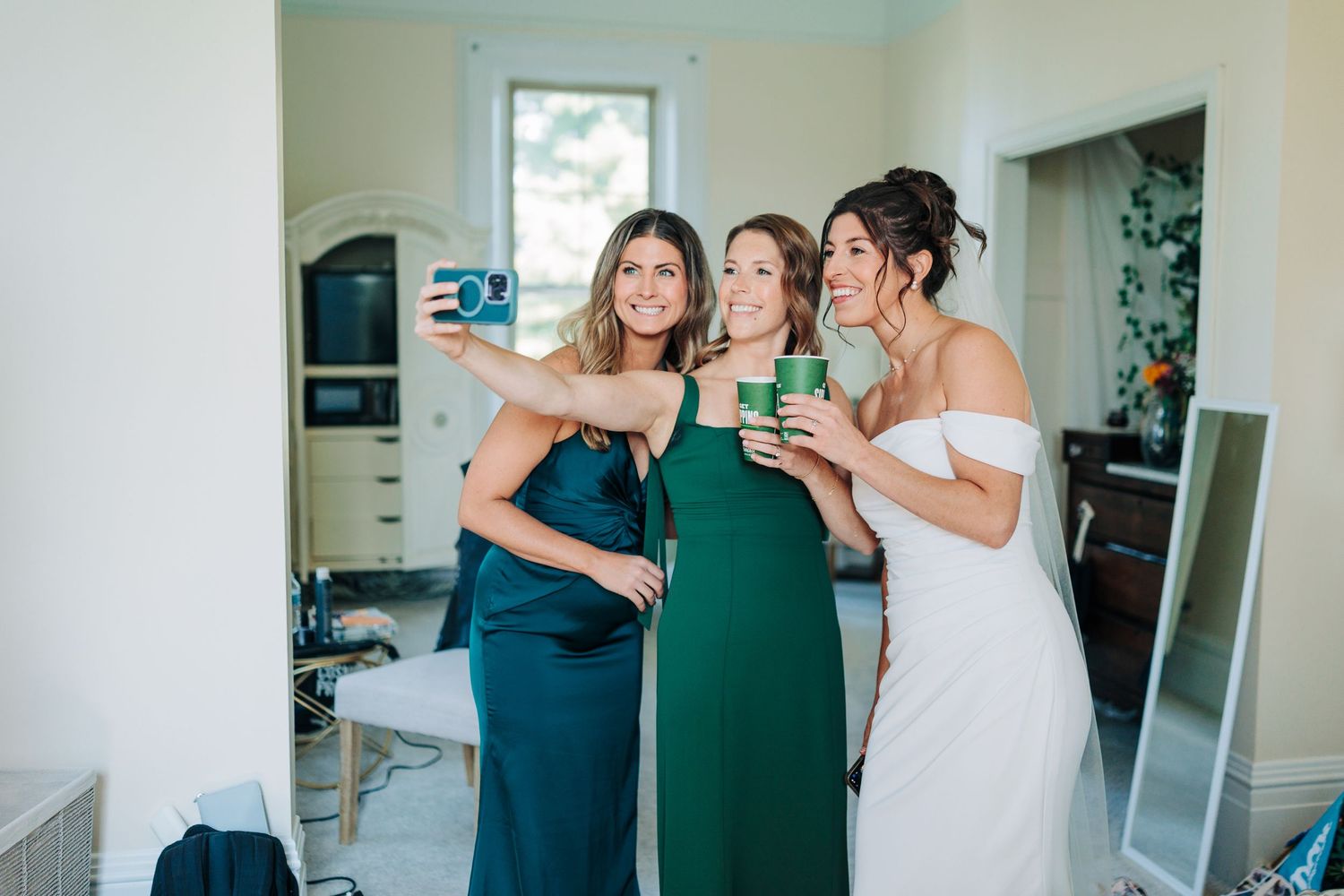 Three friends in matching green and white dresses share emotional embraces during a special celebration.