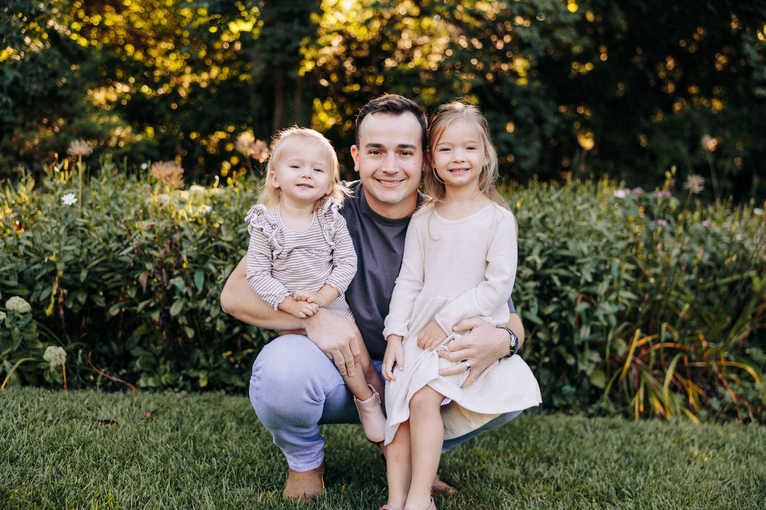 Family enjoying sunset photo session in garden with golden flowers.