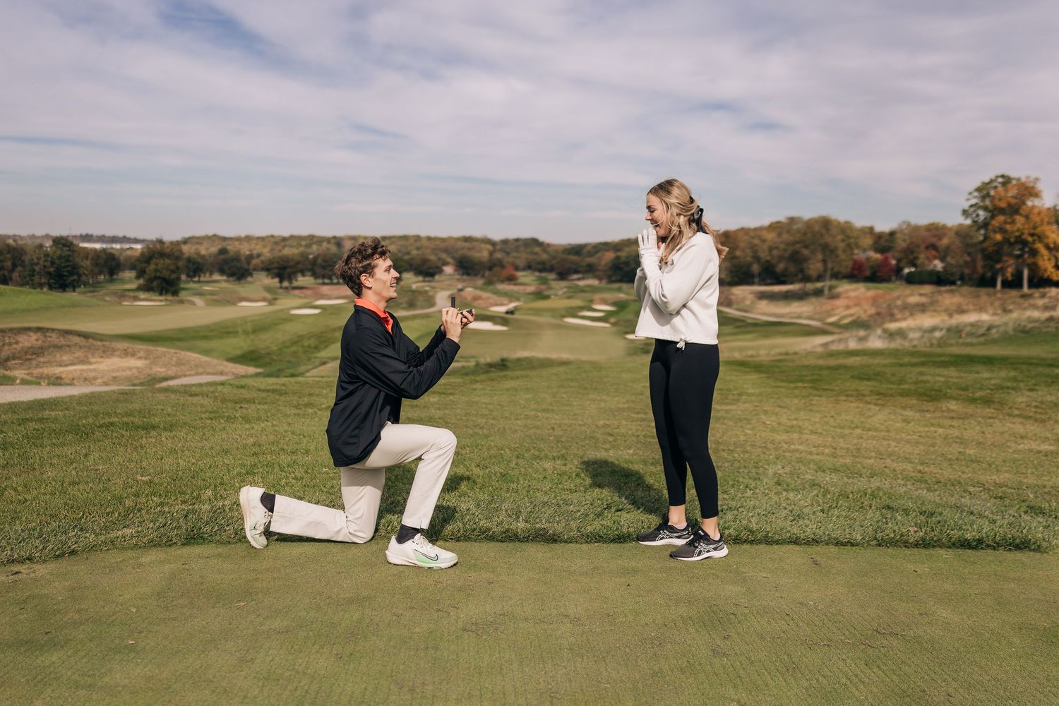 A proposal moment on a golf course with rolling hills in the background.