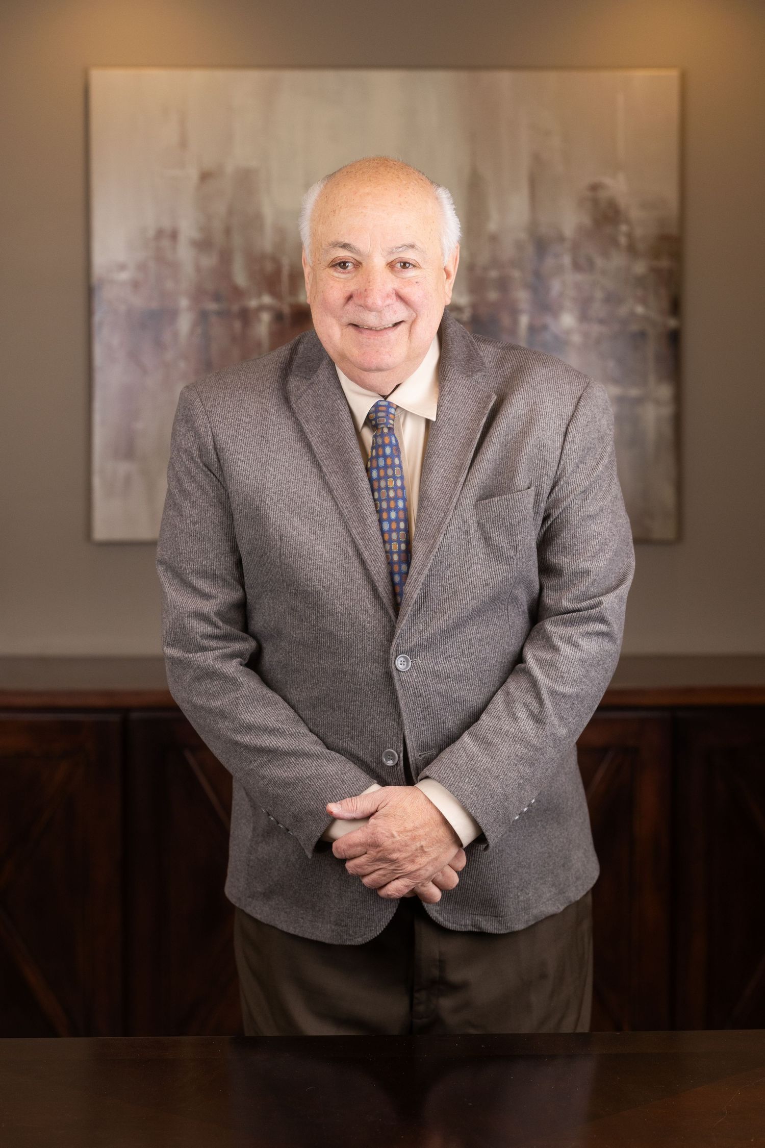 Professional headshots series in grey suit against neutral office background.