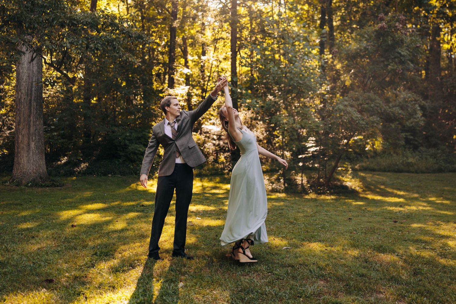 A couple dancing together in a sunlit forest clearing.