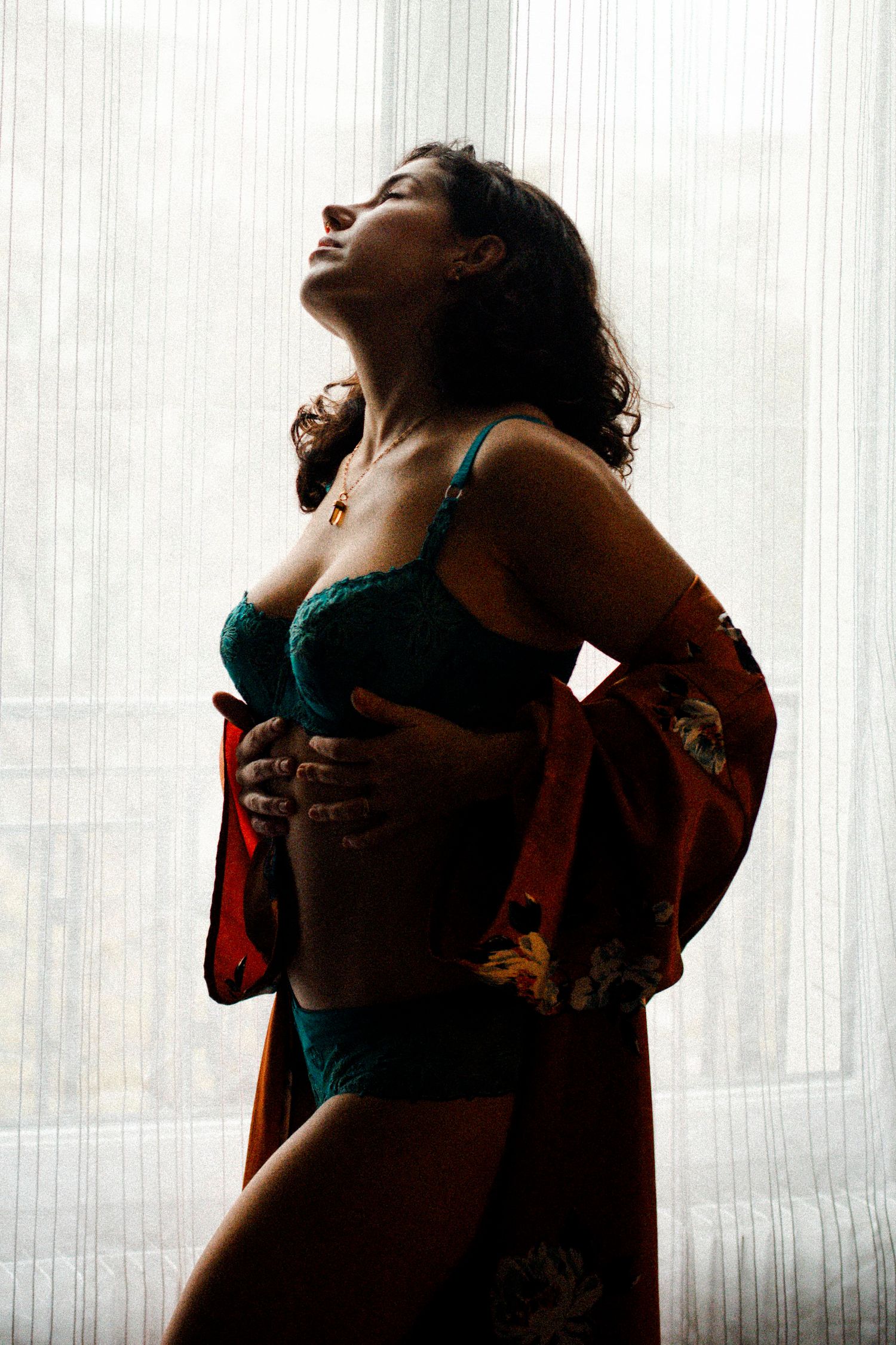 Photo intimiste en contre-jour d'une femme brune en ensemble de lingerie bleue