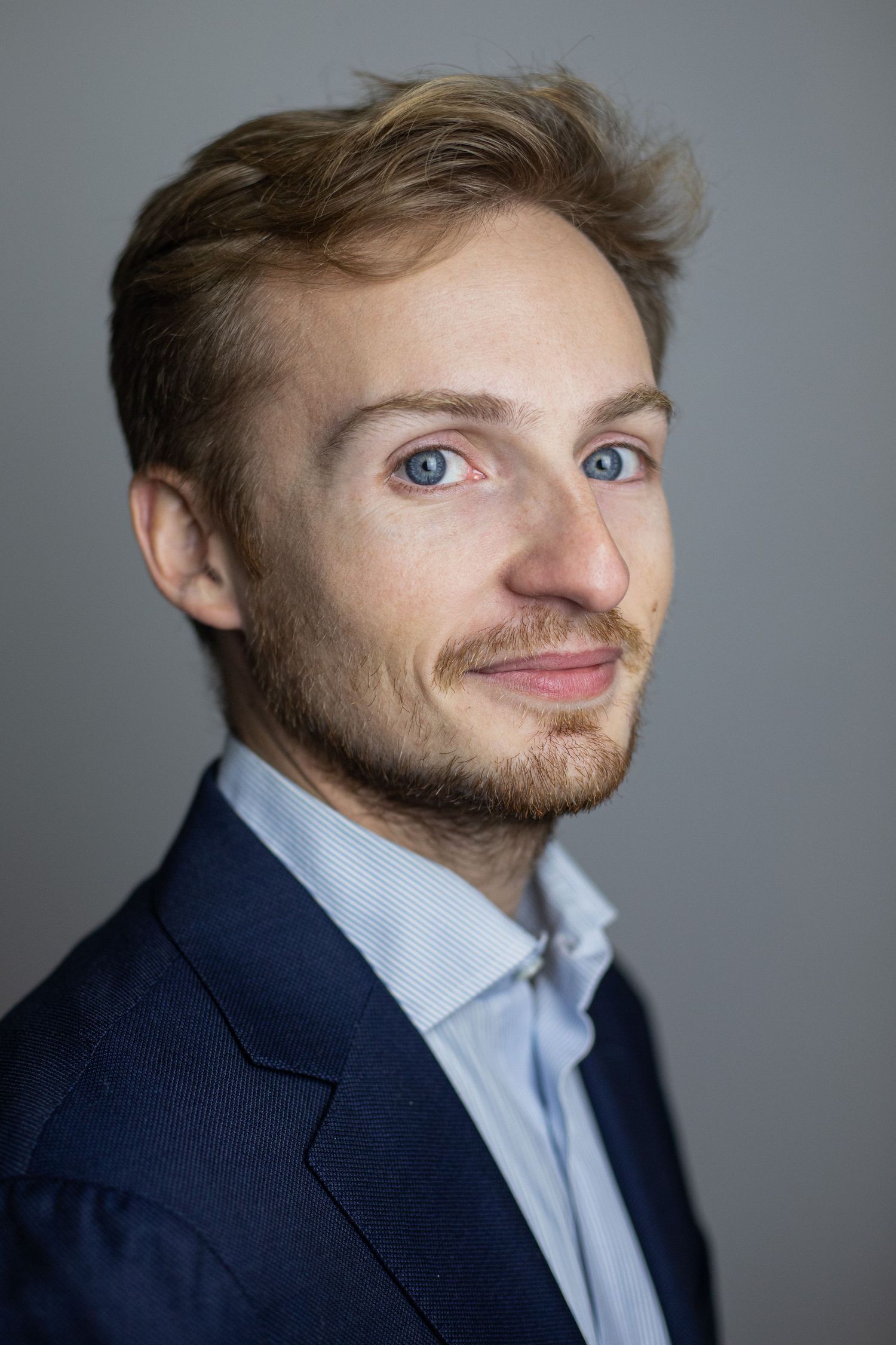 Portrait professionnel d'un homme blond en costume sur fond gris