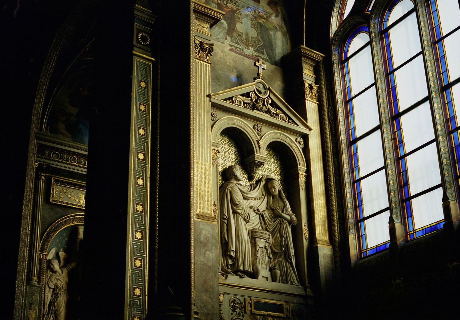 Photo argentique de l'intérieur d'une église, vitraux transparents sur la droite, sculpture murale  religieuse au centre.
