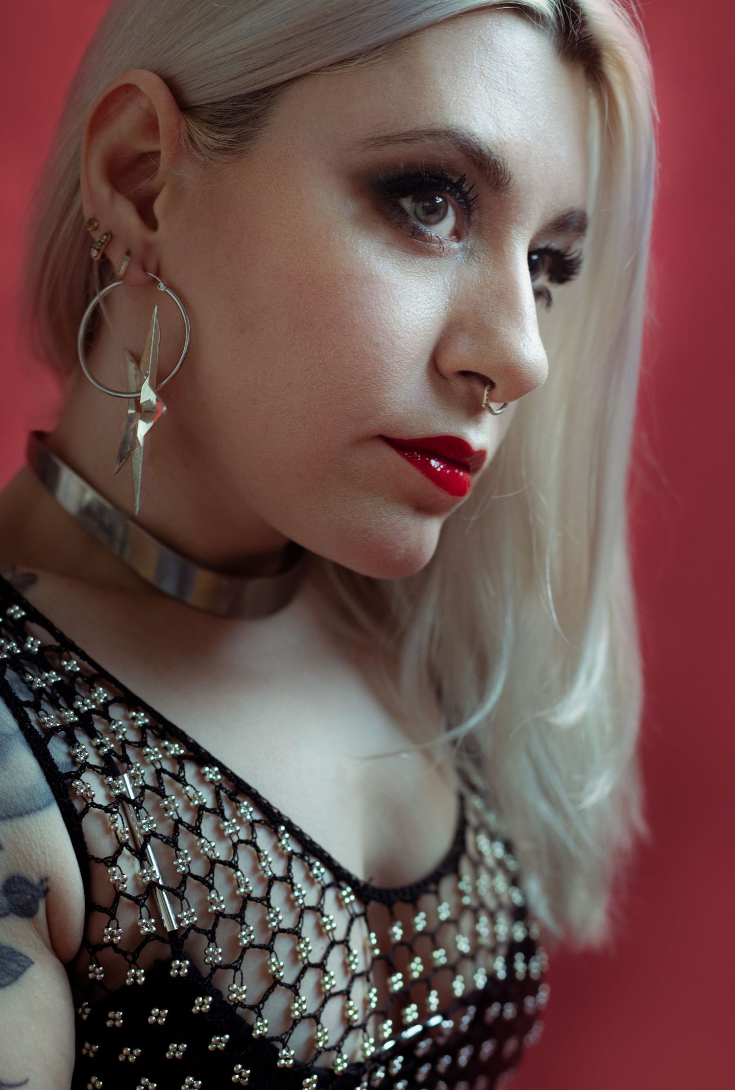 Portrait studio d'une femme blonde dans un look rock'n'roll sur fond rouge