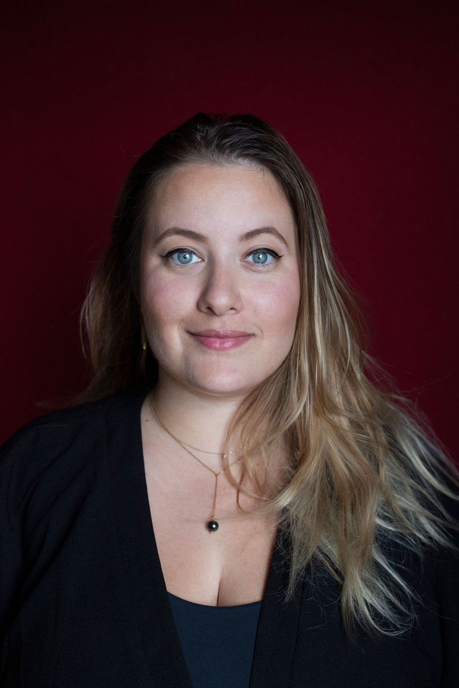 Portrait professionnel d'une femme blonde, de face, sur fond rouge