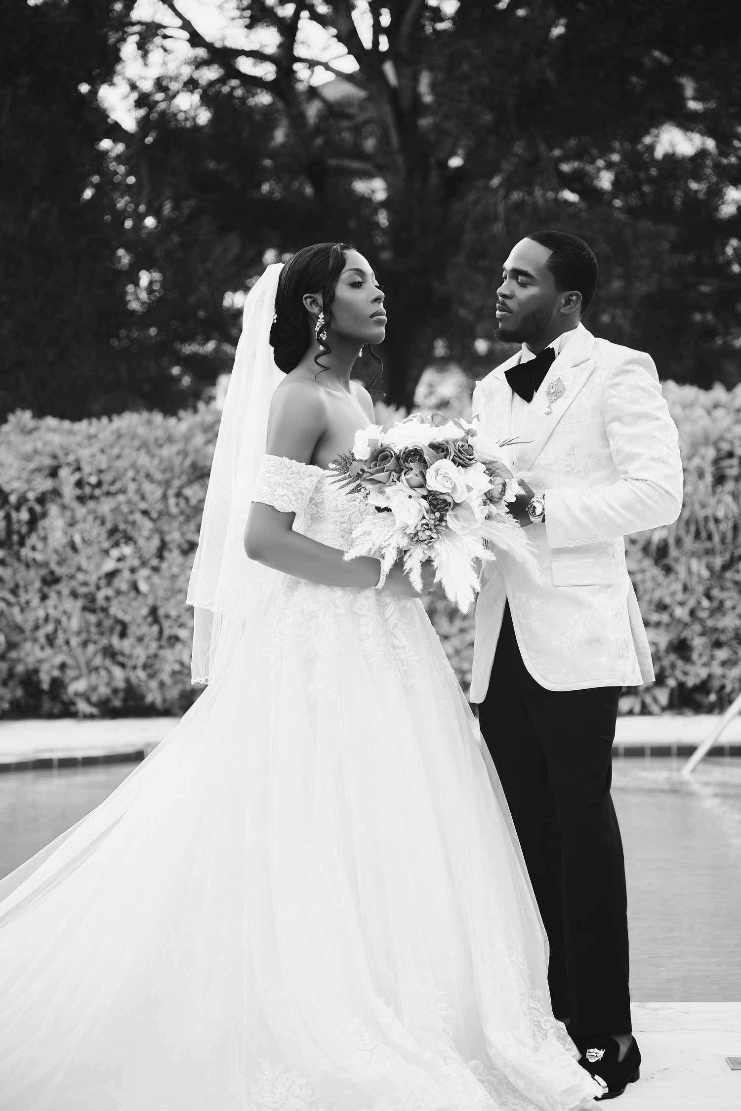 Black and white wedding photo of couple in white tuxedo and traditional bridal gown.