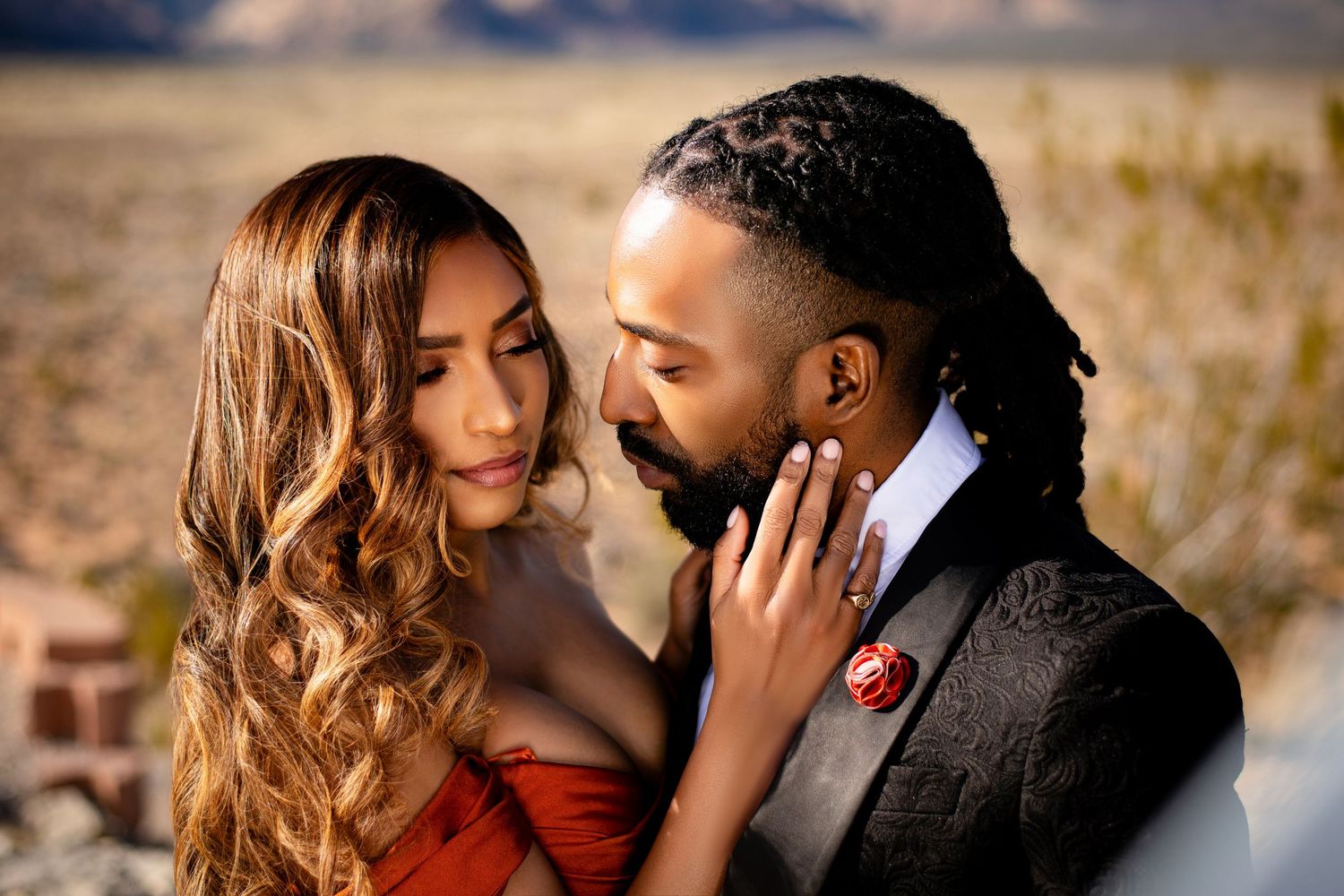 A romantic desert photoshoot featuring formal attire and intimate poses at sunset.