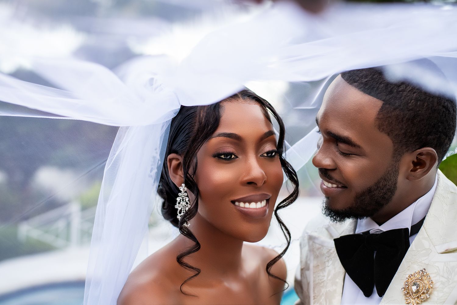 Happy newlyweds share an intimate moment under a wedding veil.