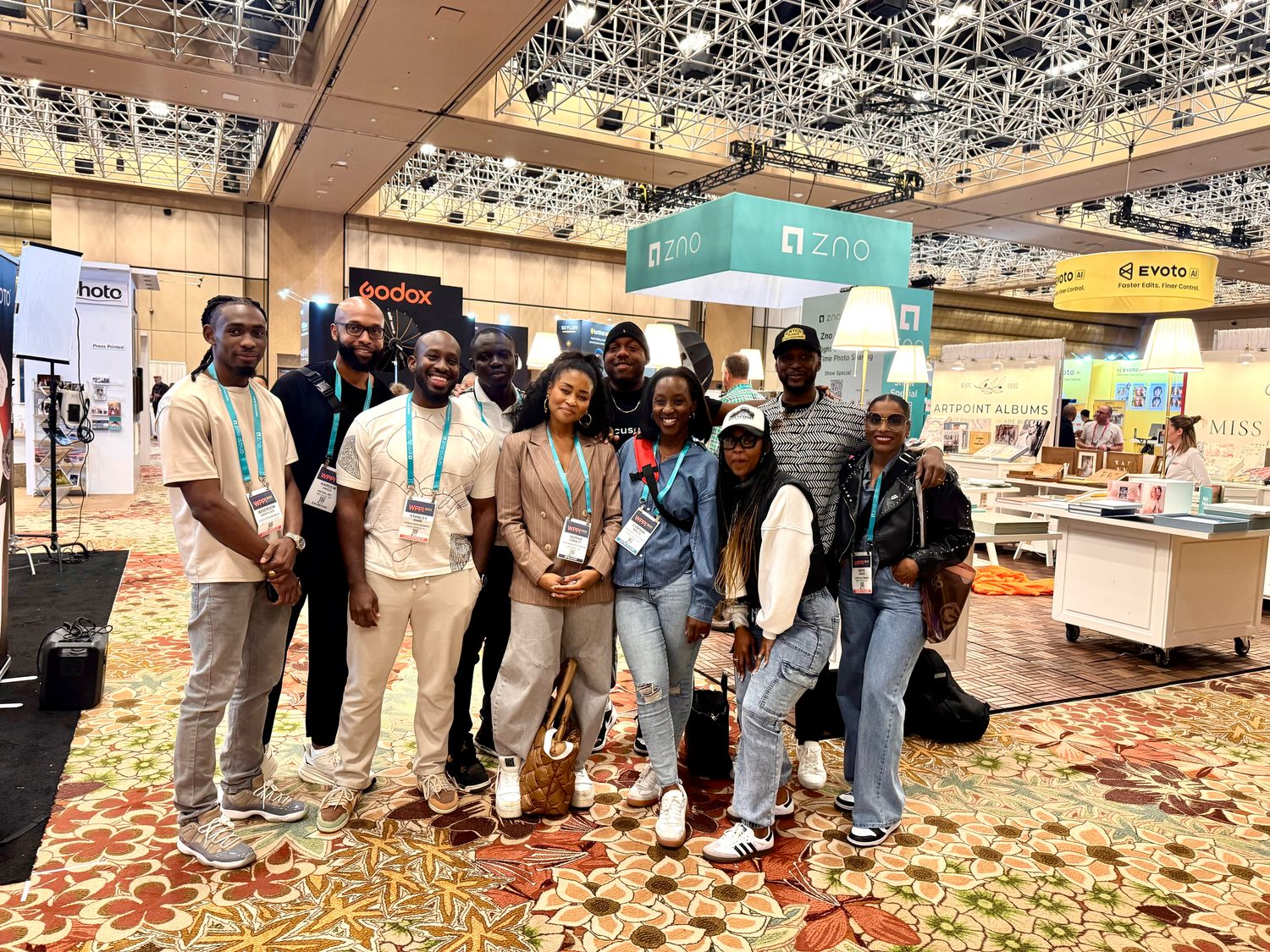 Group photo of conference attendees standing together in exhibition hall with vendor booths.