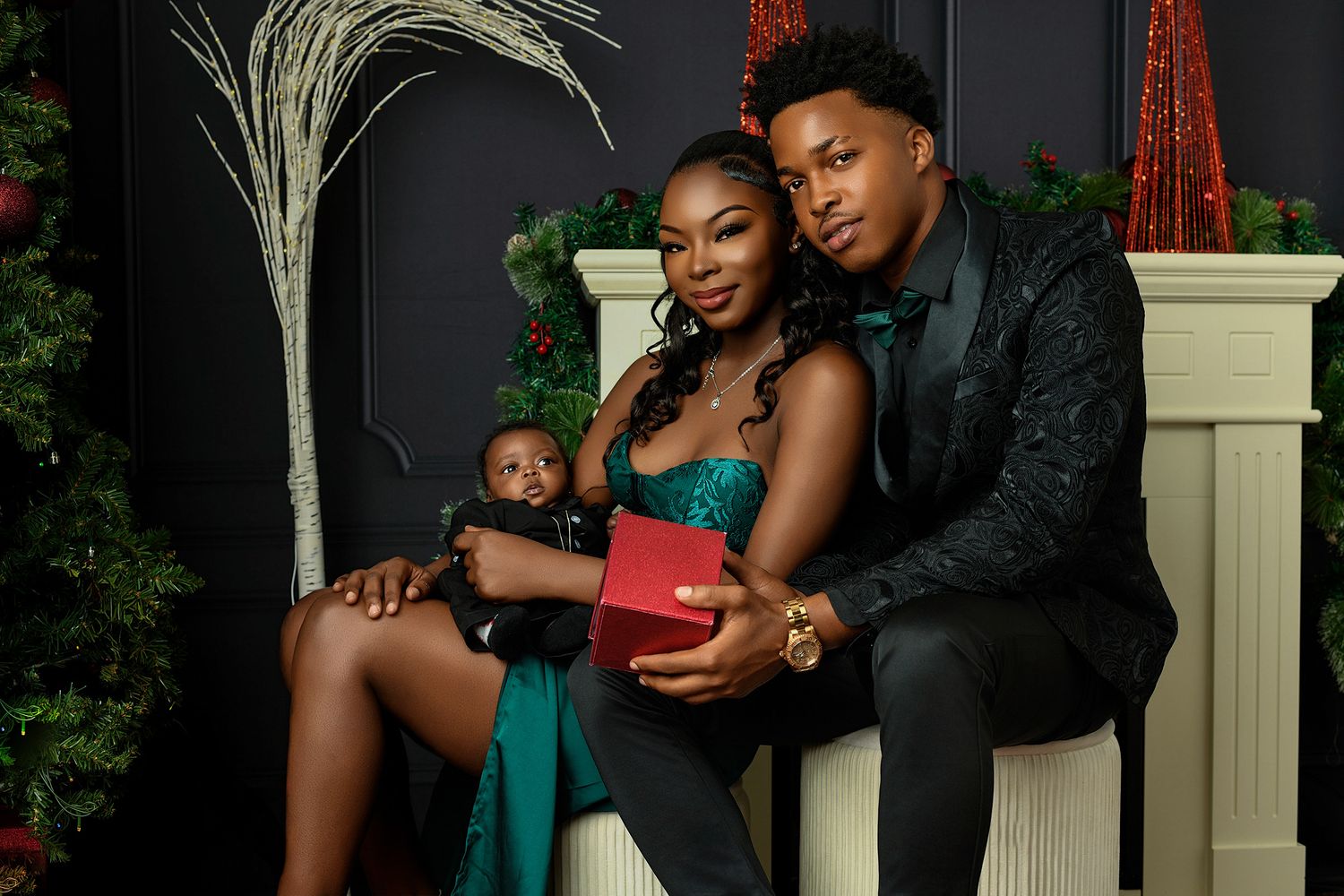 A family poses together in formal attire by a decorated fireplace and Christmas tree.