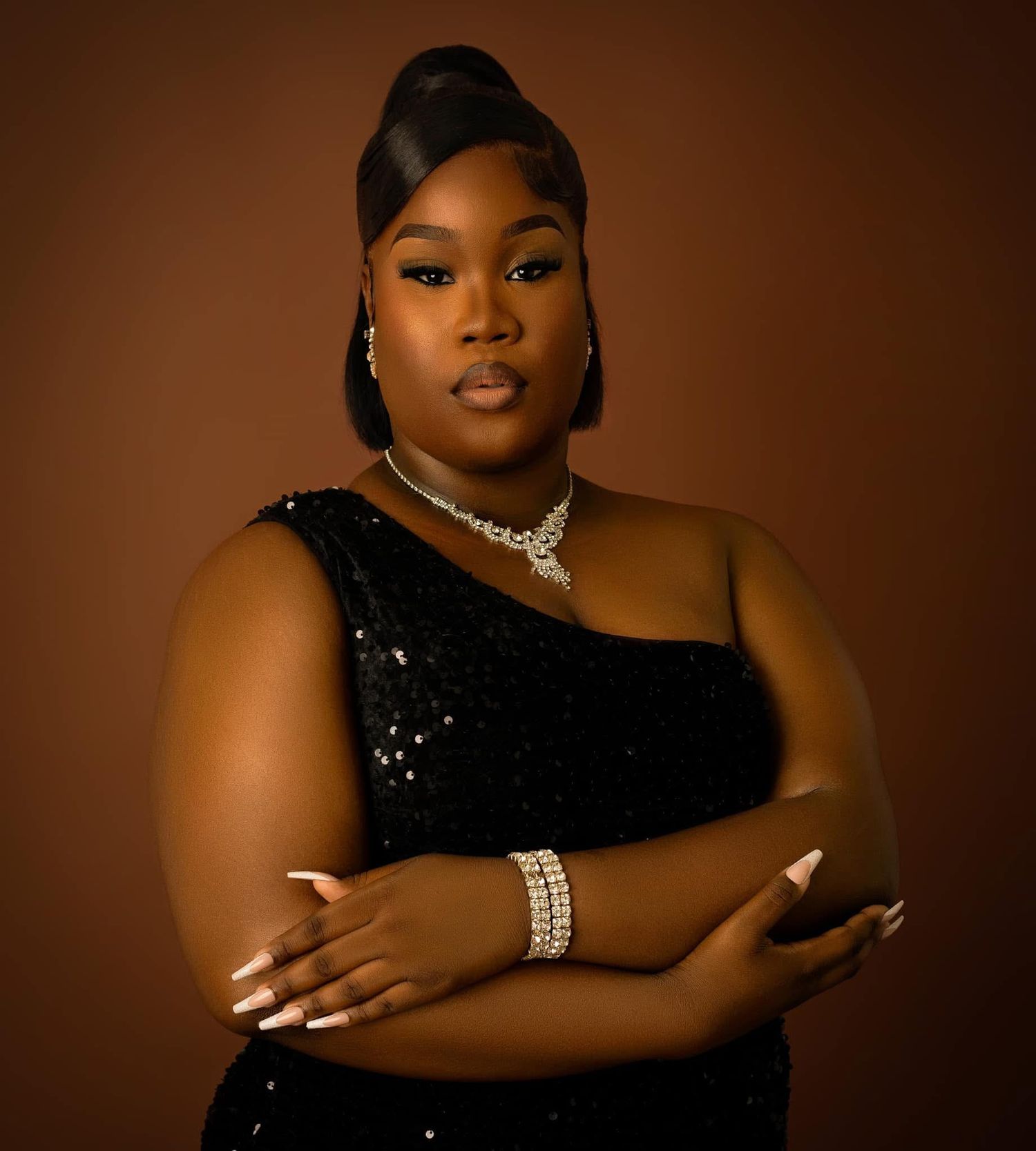 A glamorous portrait featuring a one-shoulder black sequin dress and elegant jewelry against a brown backdrop.