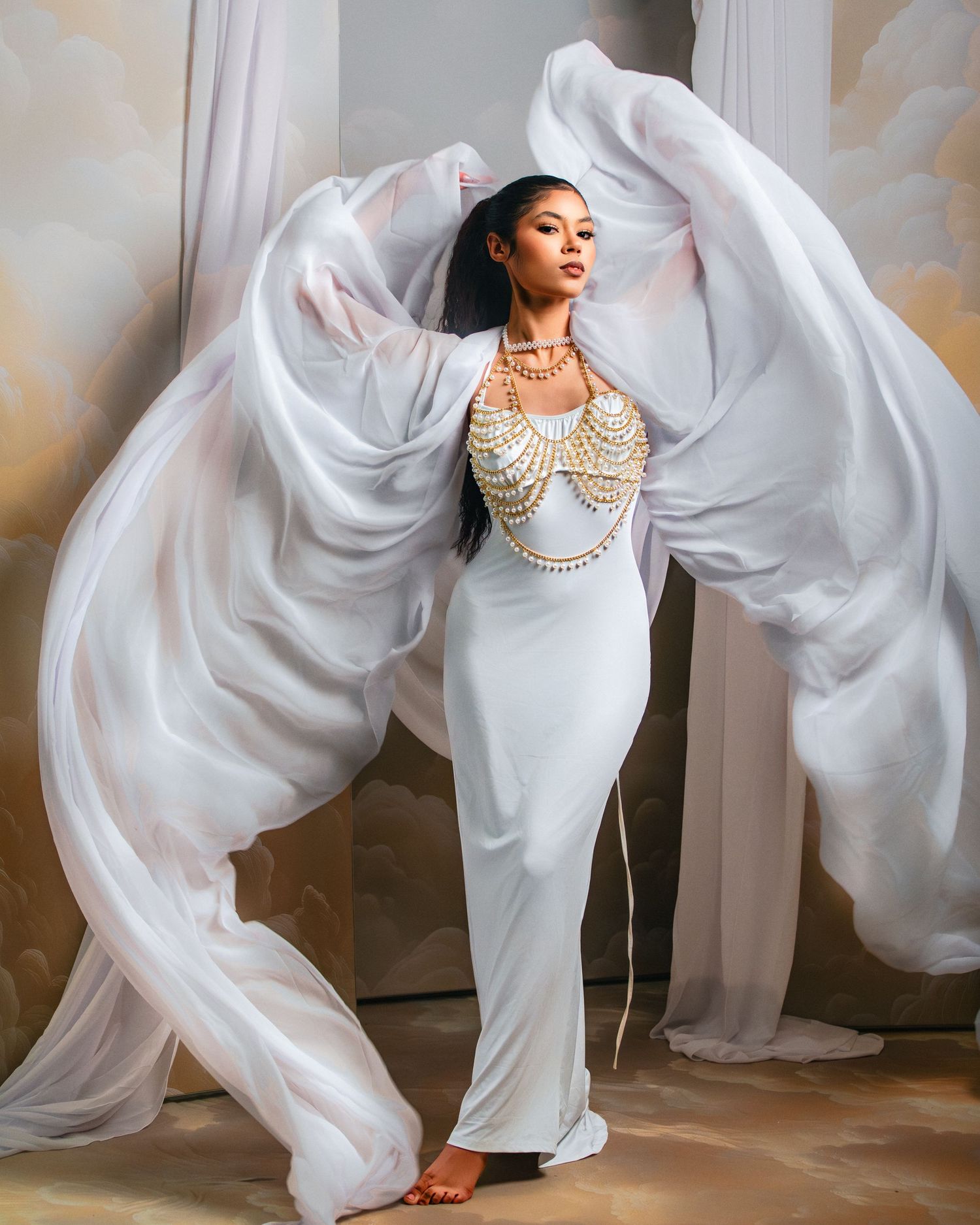 Fashion photo of flowing white dress with dramatic fabric movement and pearl body jewelry.