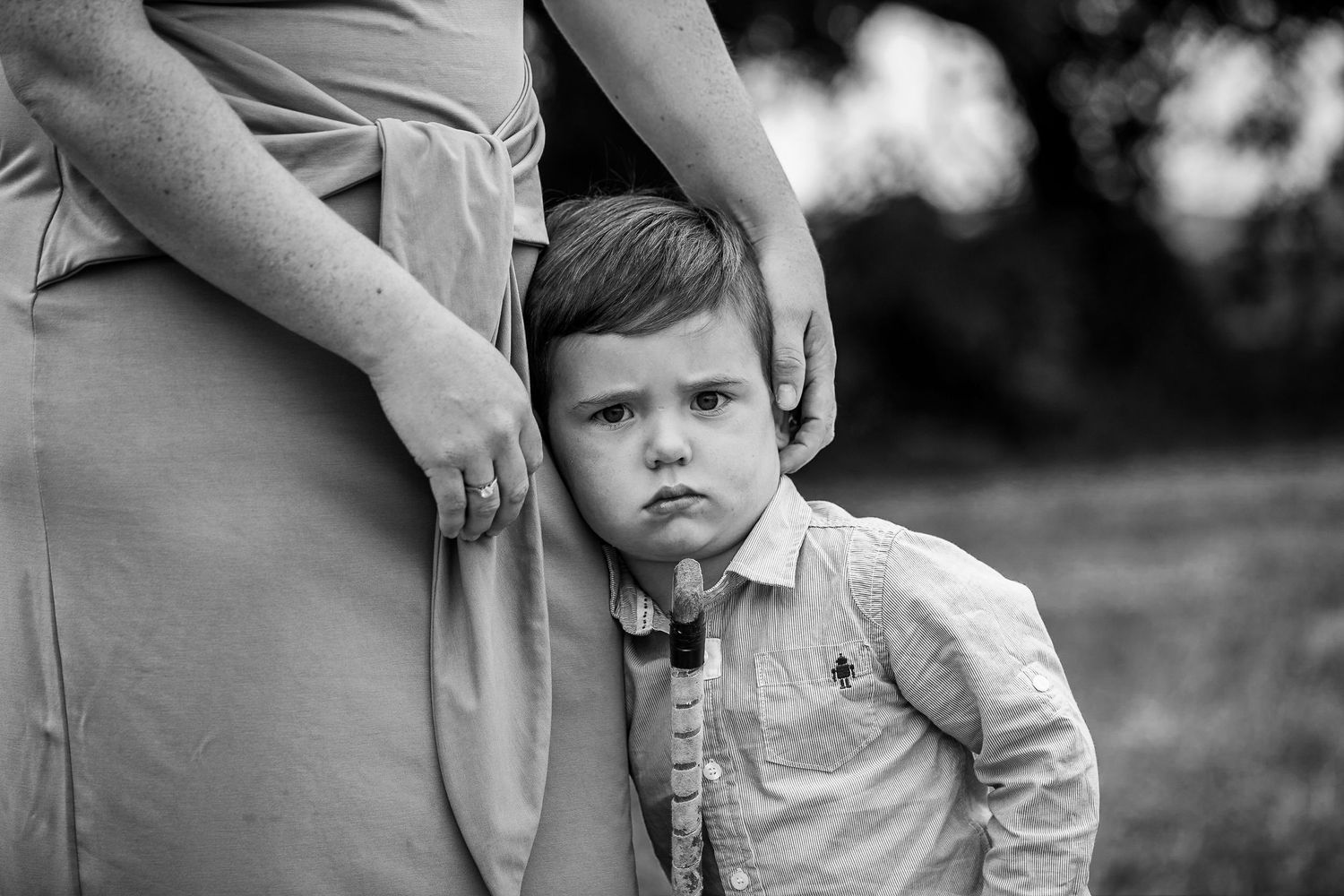 Black and white portrait showing protective gesture in an outdoor setting.