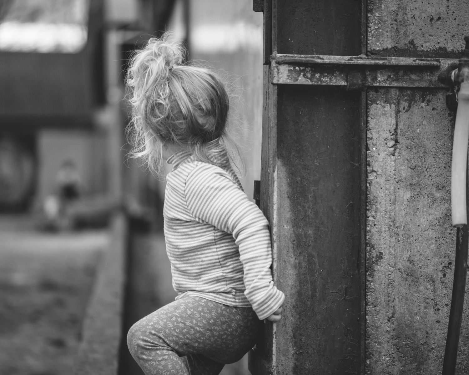 Black and white photo of small child climbing on outdoor equipment.