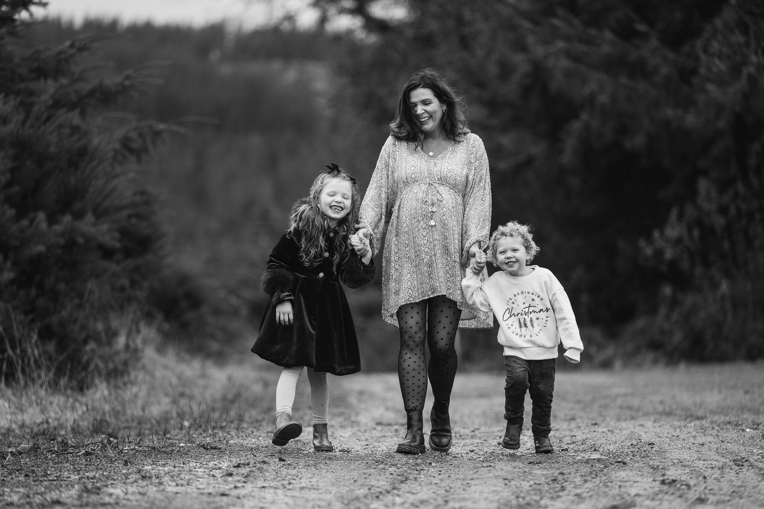 Family walking together on a dirt path through nature in black and white.