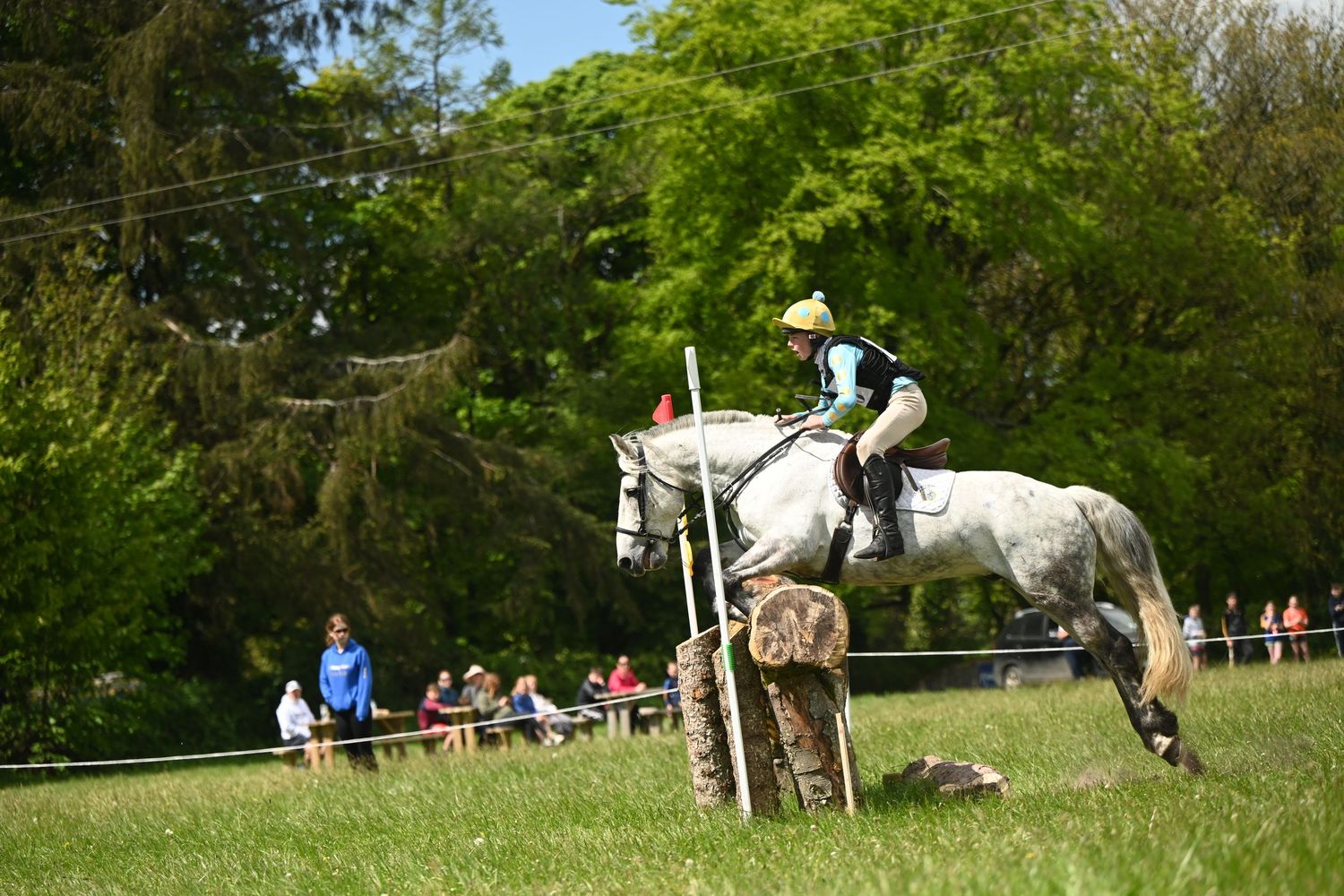 Horse and rider clear a jump during an equestrian event with spectators watching.