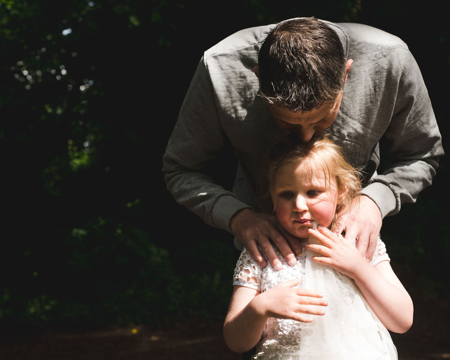 Tender moment between parent and child captured in natural sunlight.