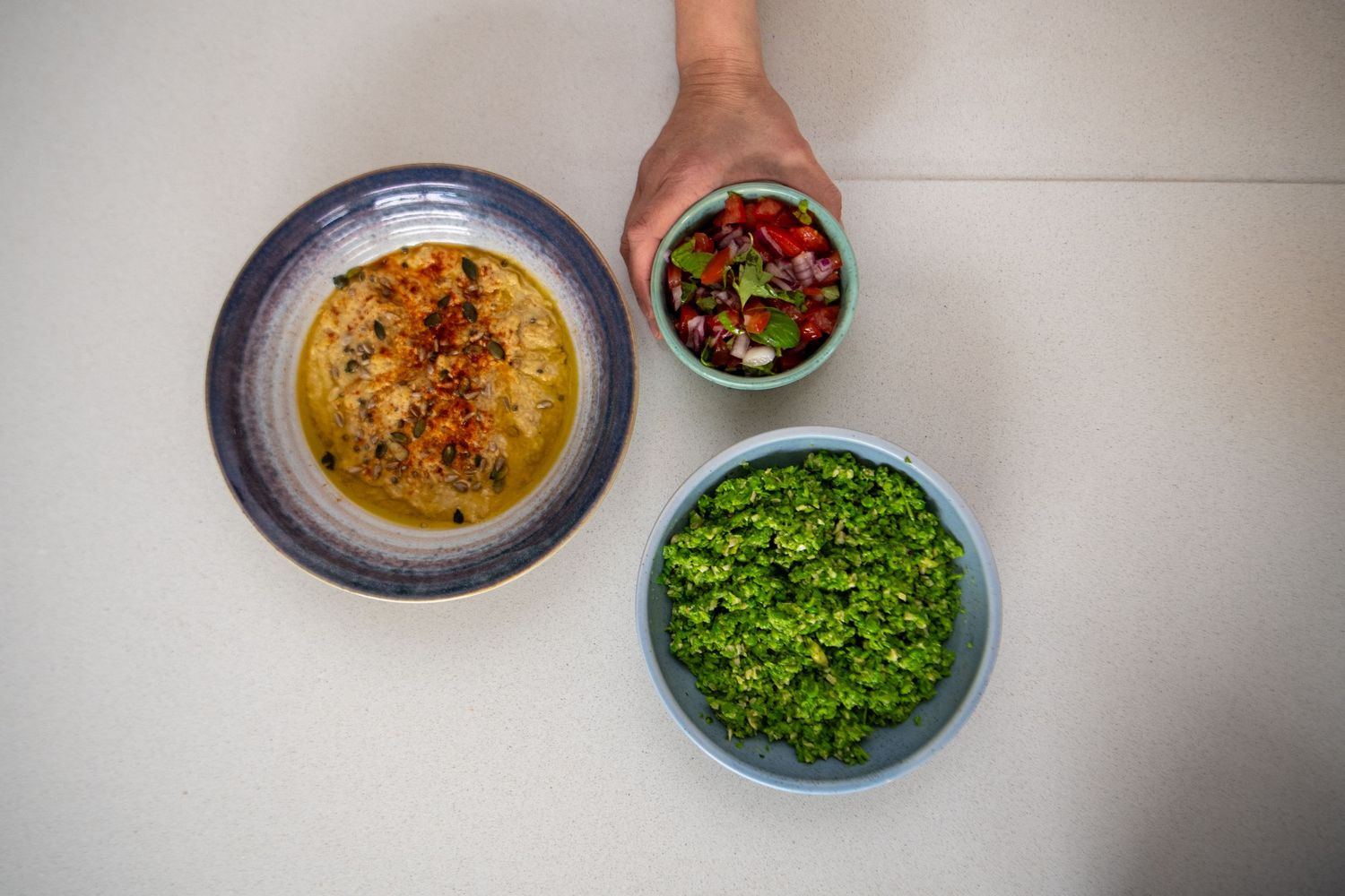Series of garnished soups and side dishes arranged on a white countertop.