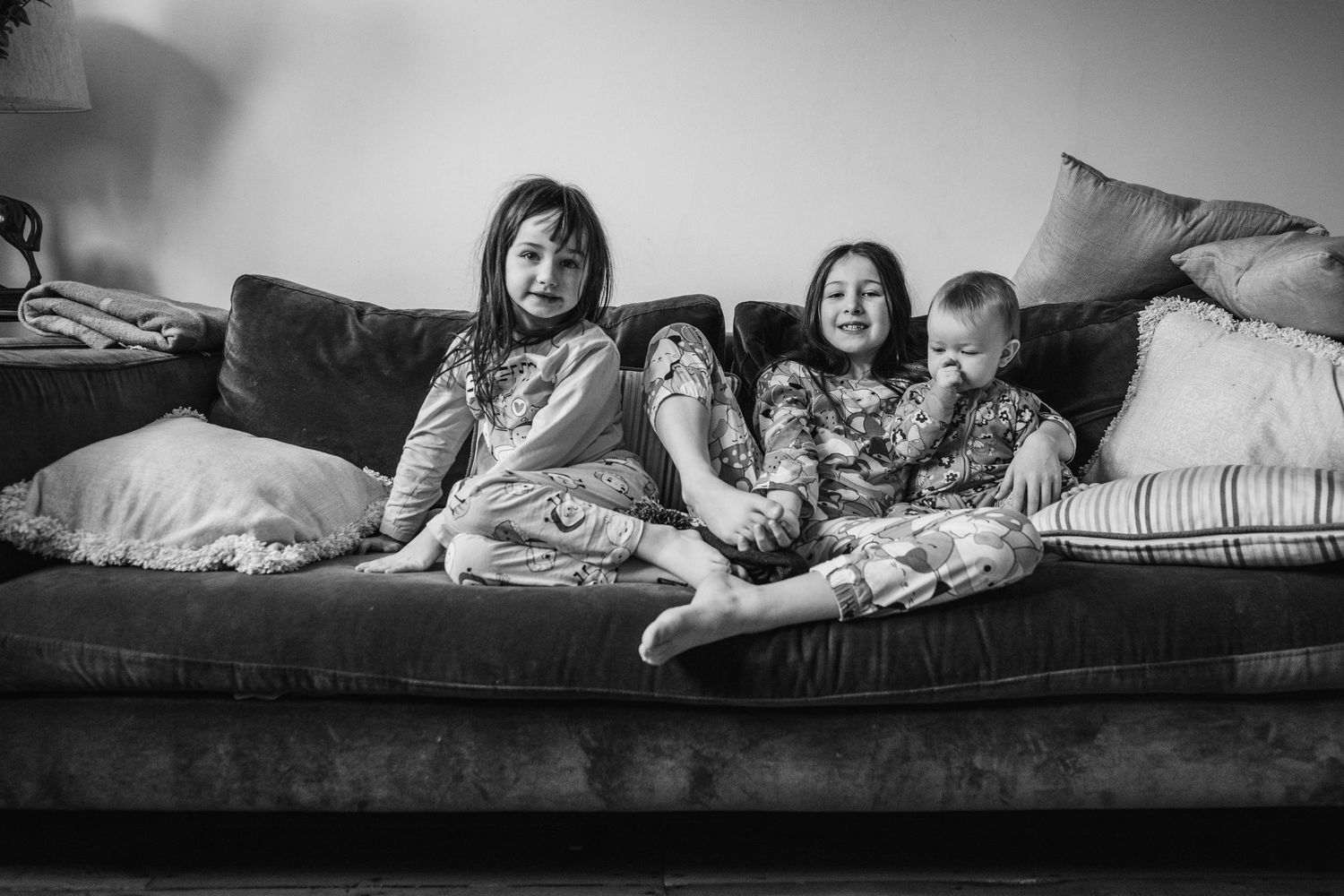 Family relaxing together on a cozy couch in black and white.