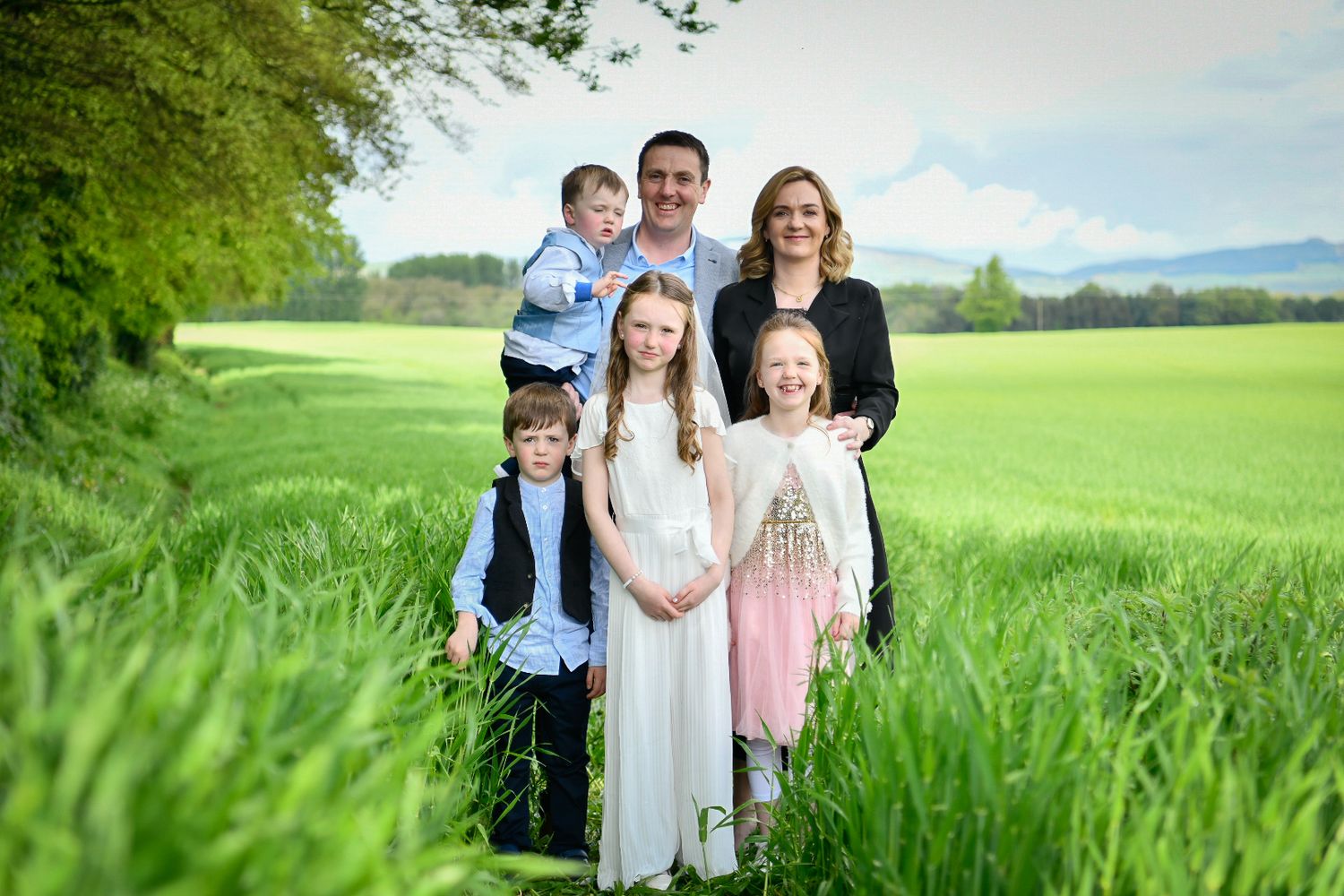 Family portrait in a green wheat field on a bright summer day.