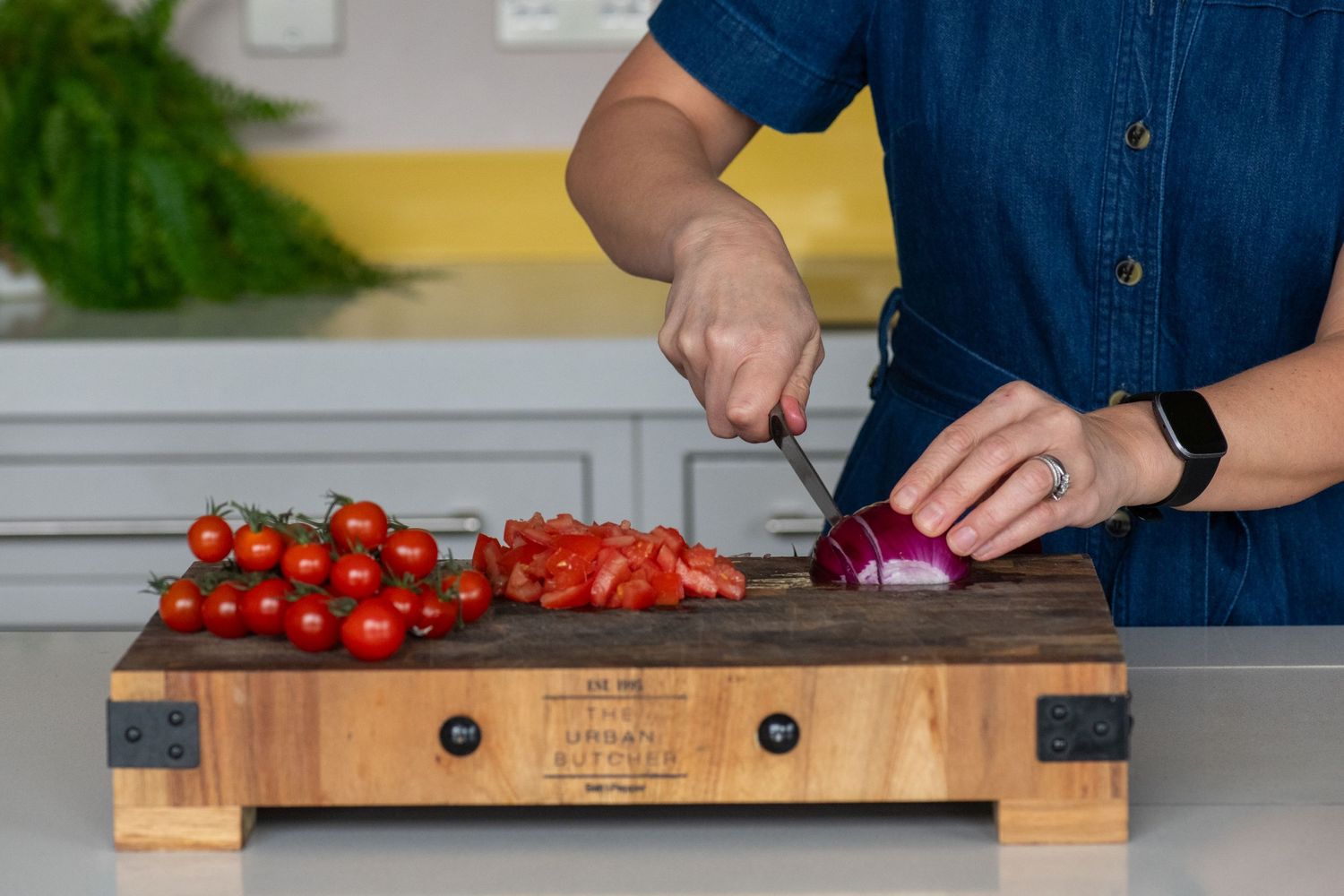 Fresh vegetables being chopped on a wooden cutting board in a bright kitchen.