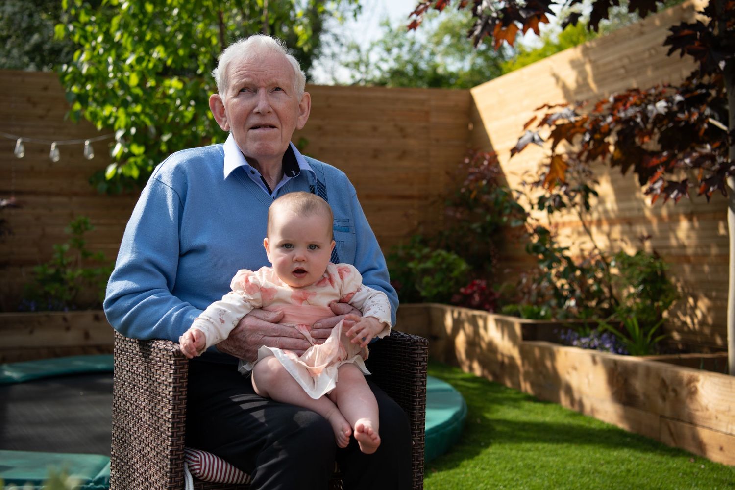 Baby and caregiver sharing tender moments in a backyard garden setting.