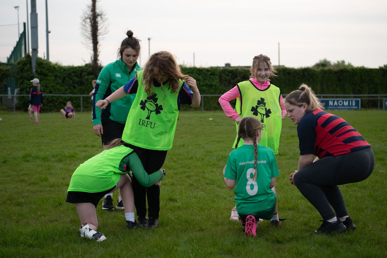 Soccer players train on a grass field wearing bright green and striped jerseys.