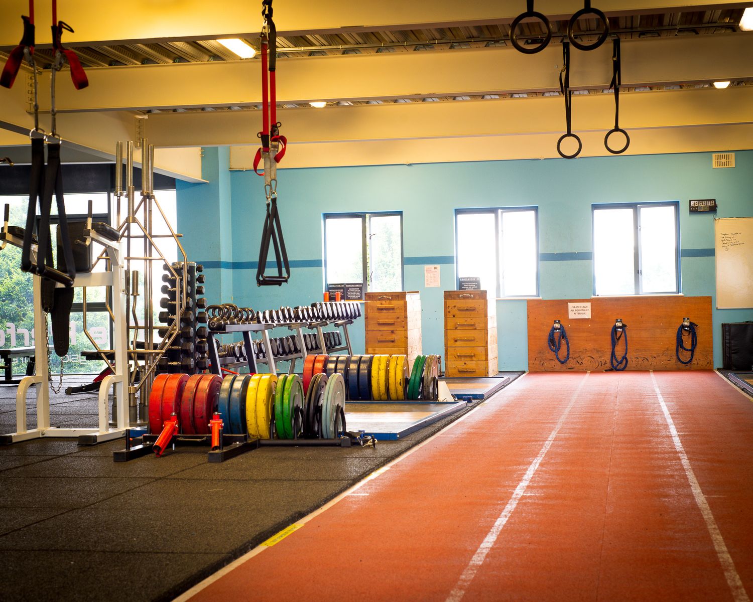 Long view of an indoor fitness facility with colorful weight plates and training equipment.