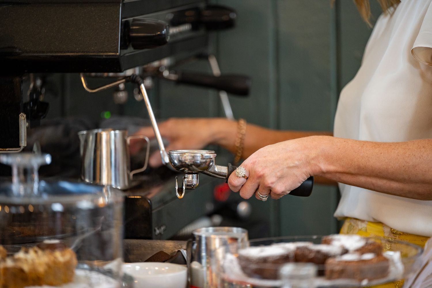 Hands operating professional coffee equipment in a cafe setting.