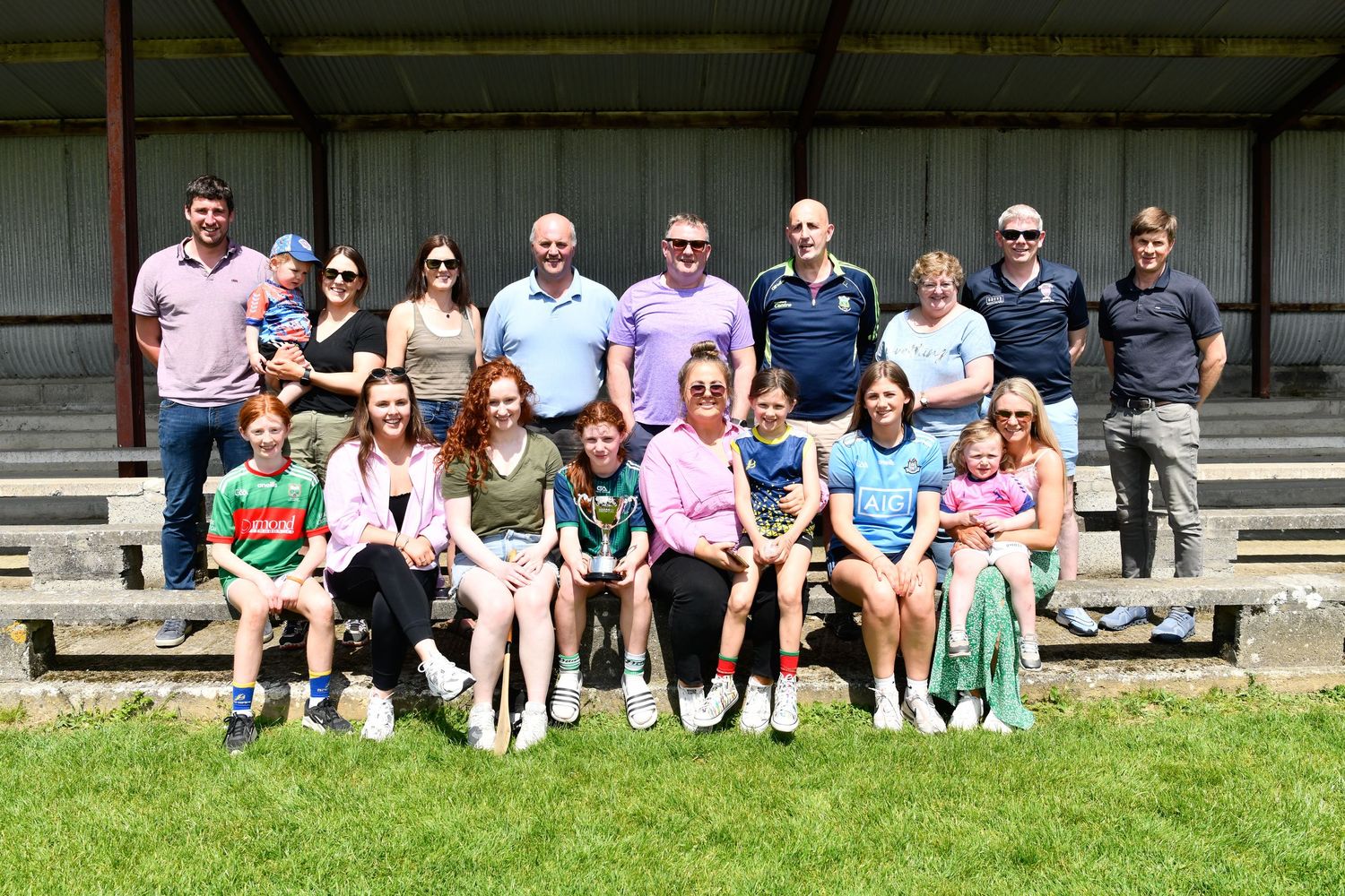 Extended family sitting together on outdoor bleacher seating.