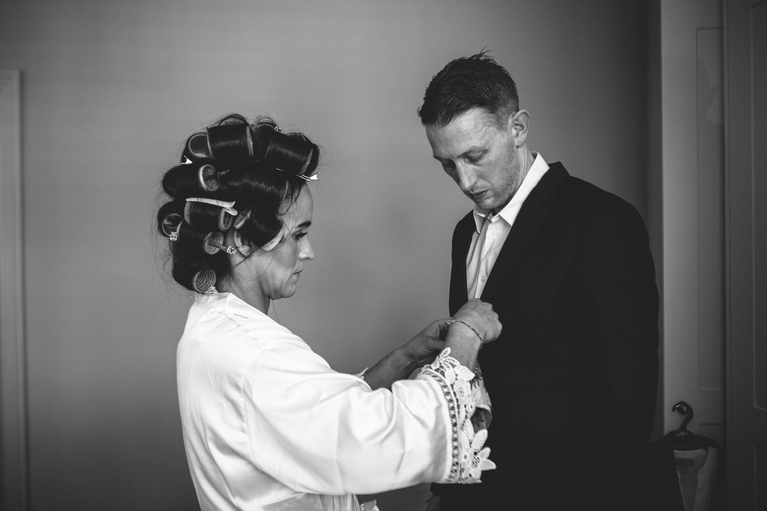 Black and white image showing wedding preparation with hair in rollers.