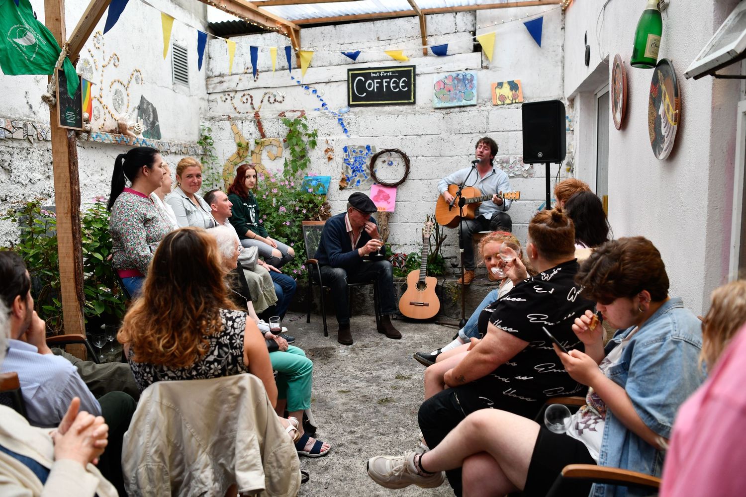 Outdoor garden party with string lights and people enjoying live music.