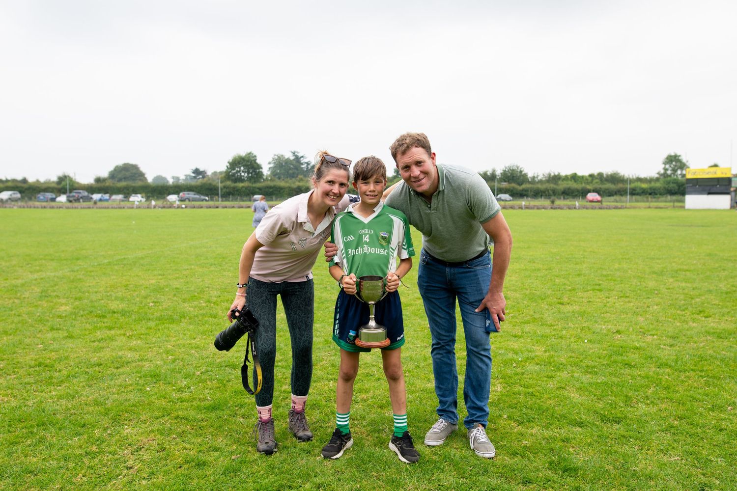 Family group photo session taking place on a sunny day in a green field.