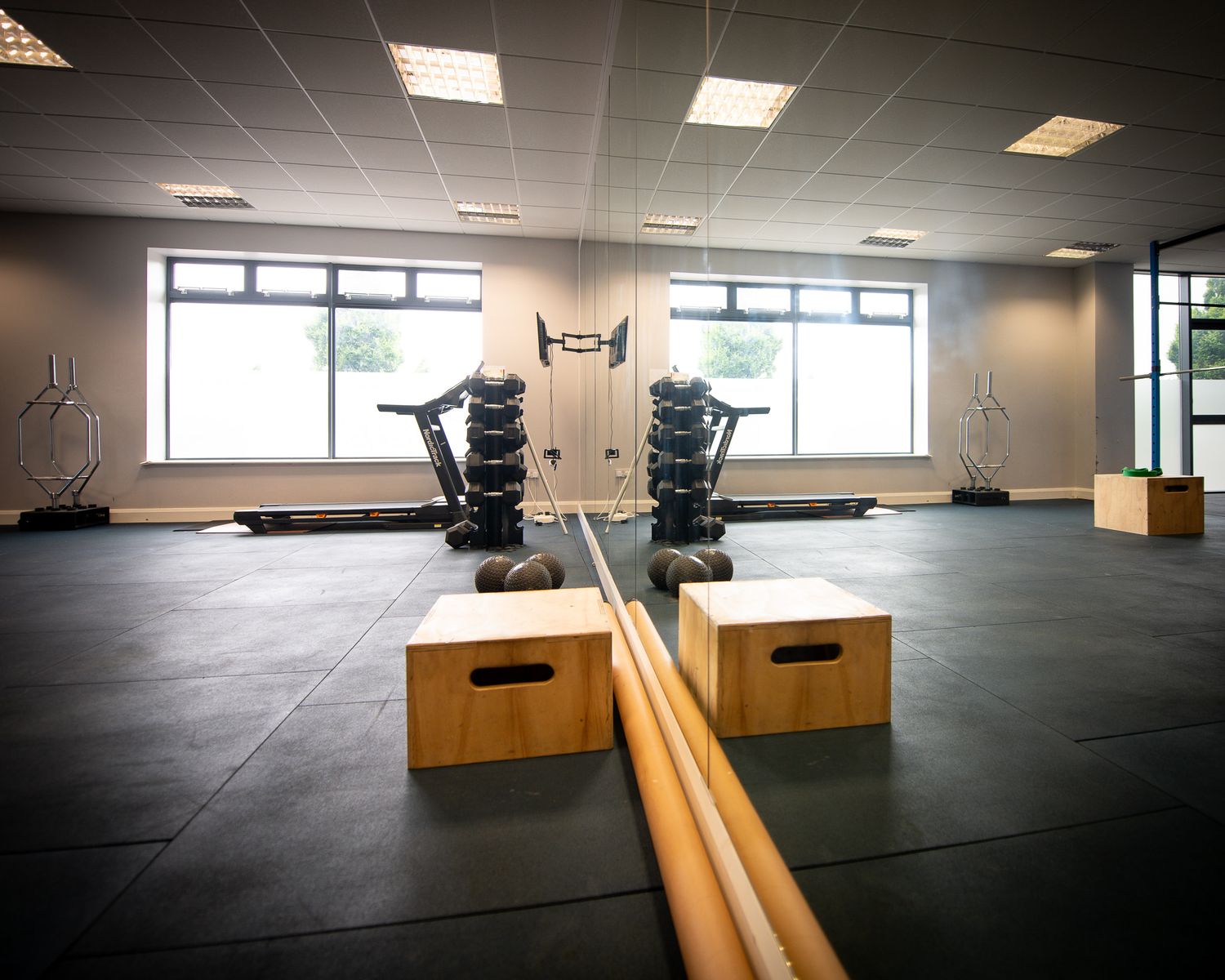 Modern fitness facility with black rubber flooring and wooden plyo boxes arranged in an empty training space.