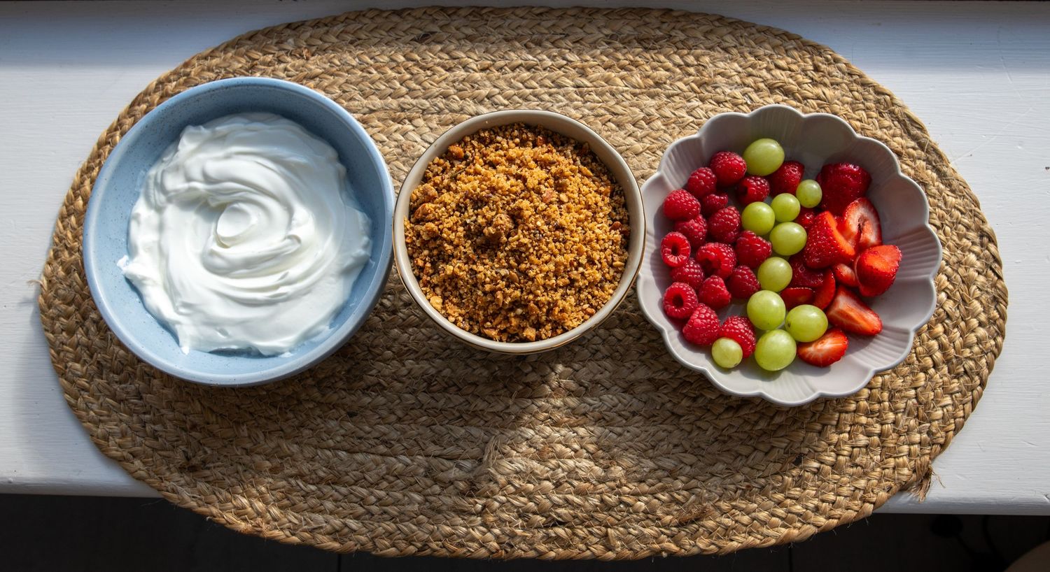 Fresh fruit and dip arranged on woven placemat with various accompaniments.