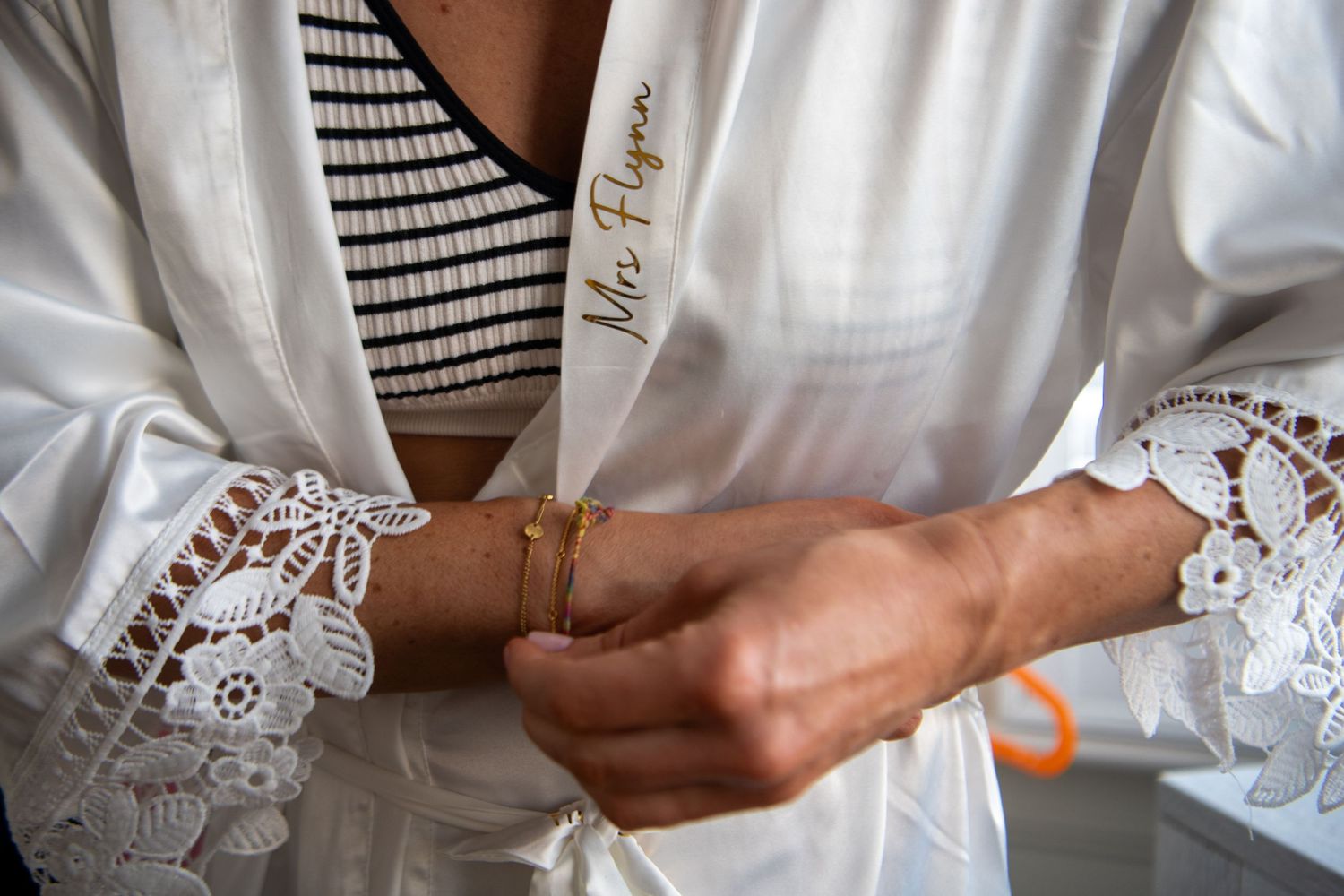 Close-up detail of lace sleeve and bracelet on white wedding robe.