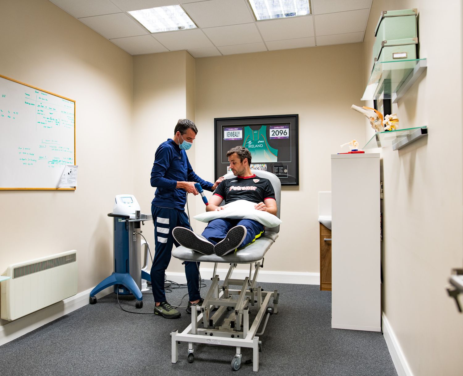 Medical treatment room with examination table and healthcare equipment.