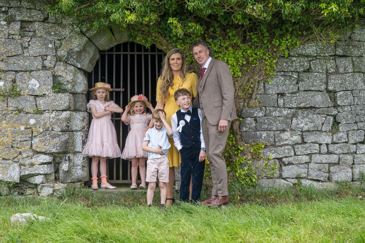 Group gathered under an old stone archway in a rustic garden setting.
