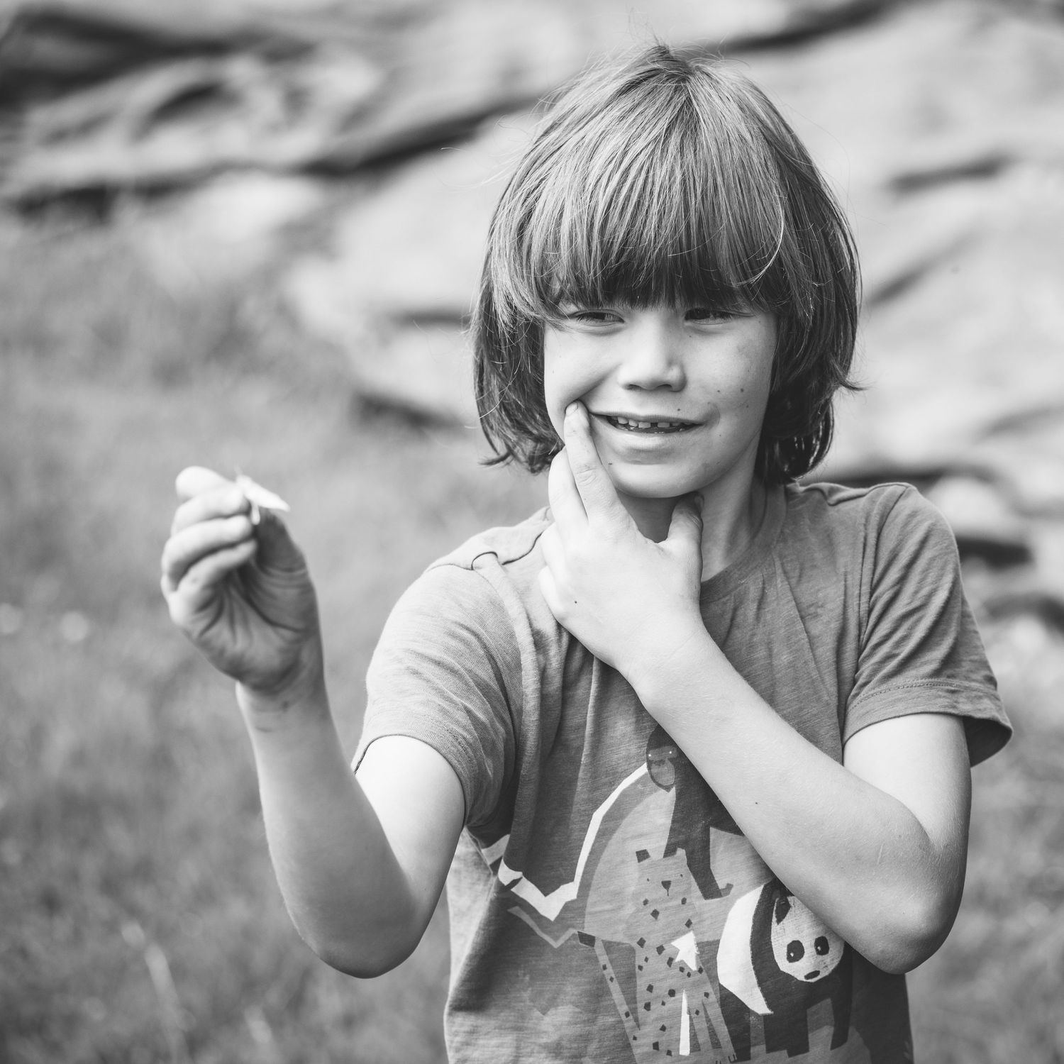 Candid black and white portrait showing joyful expression in outdoor setting.