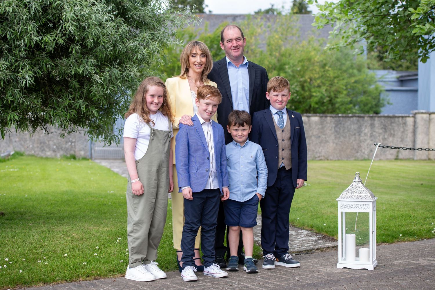 A group poses together on a grassy lawn with a decorative white lantern.