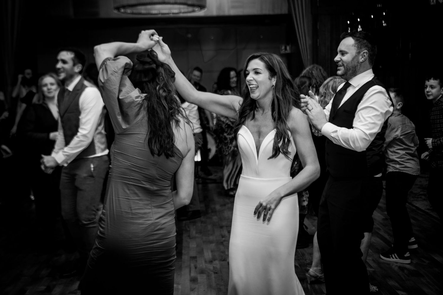 Black and white photo of wedding reception dancing with guests celebrating.