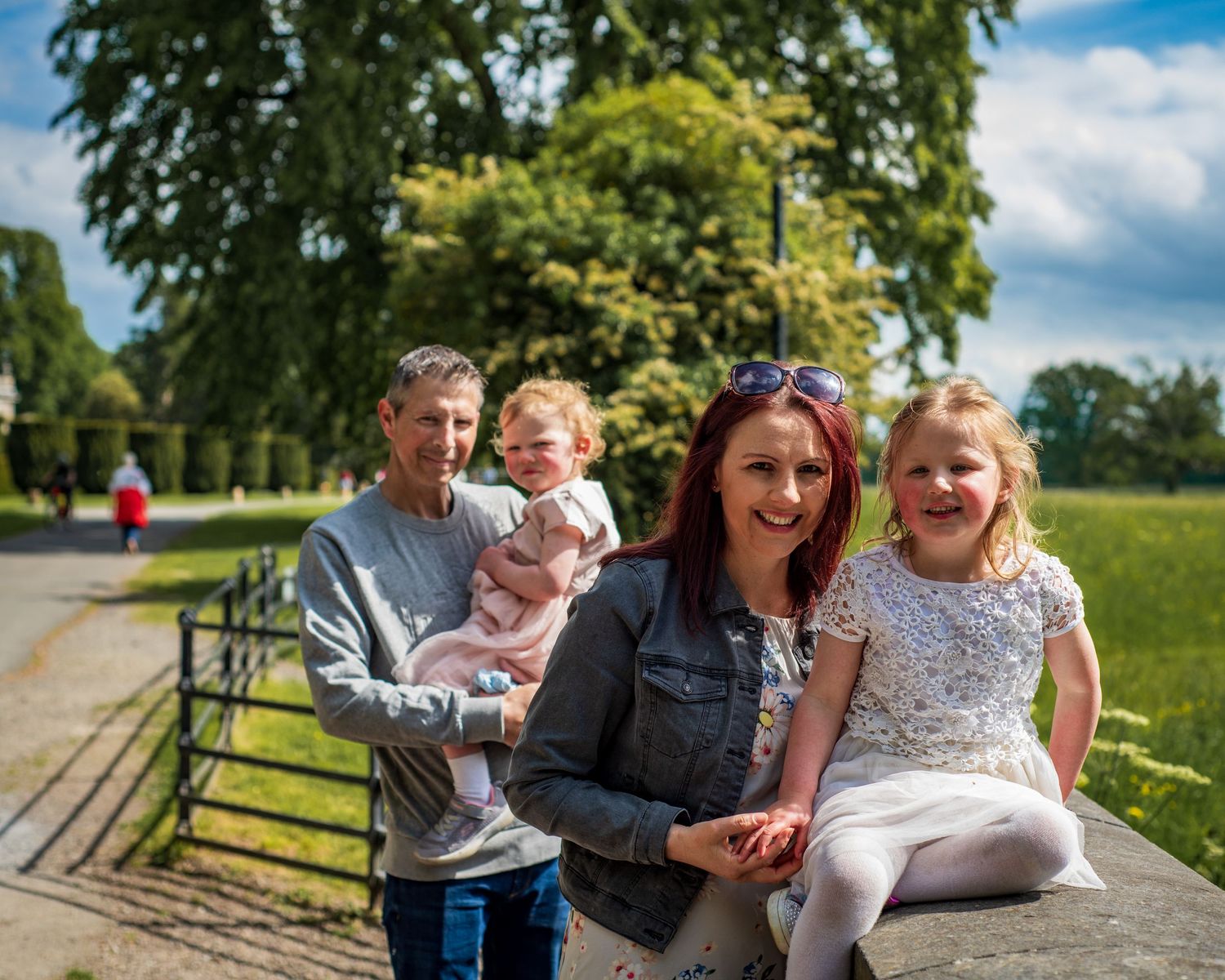 Group enjoying a sunny day together at a park with wooden fencing.