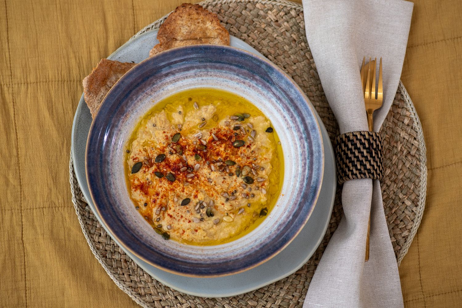 Creamy butternut squash soup served in blue-rimmed bowls with garnish on rustic placemats.