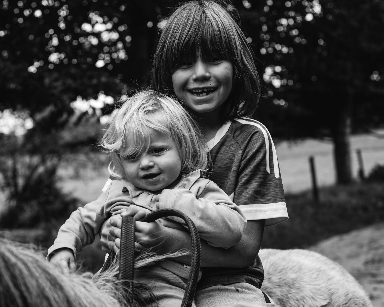 Two riders sitting together on horseback in a black and white outdoor scene.