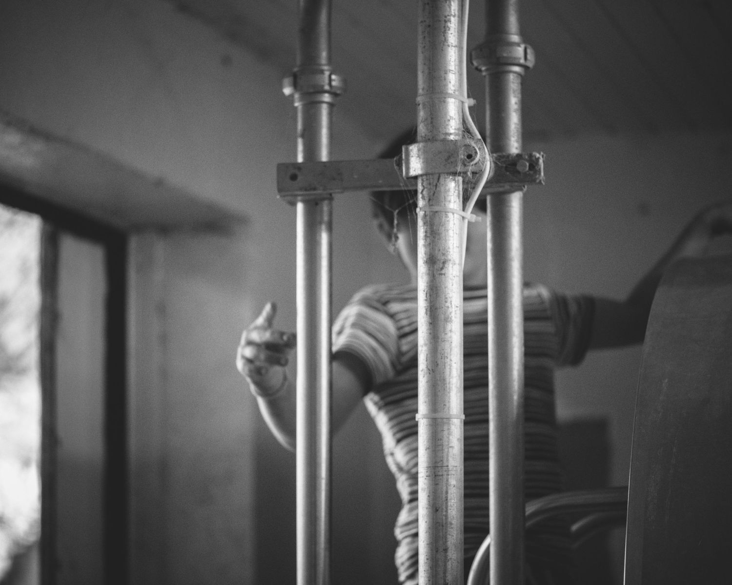 Black and white image of hands working on industrial plumbing pipes in an indoor setting.