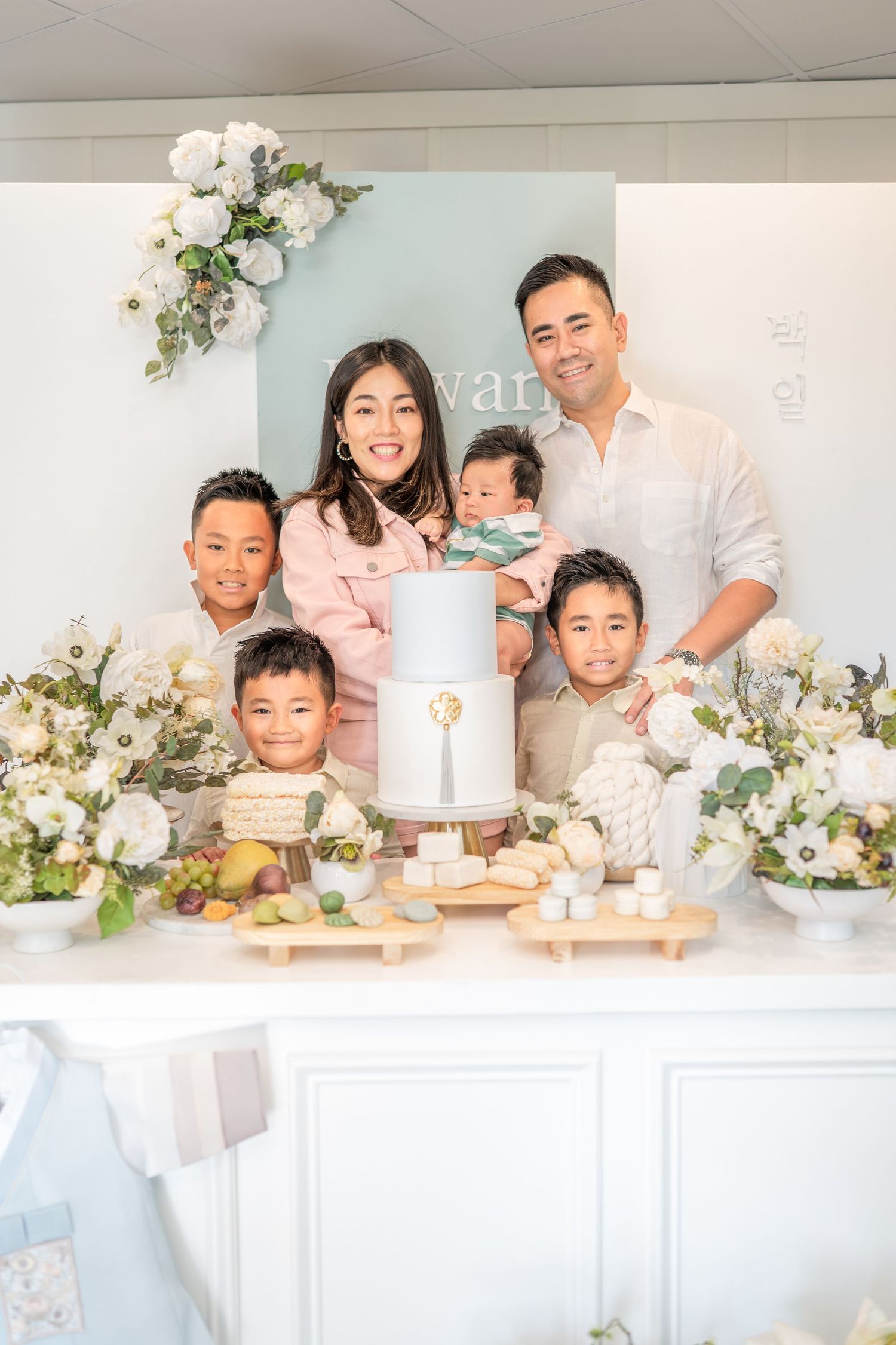 Family baking and decorating cakes together in bright white kitchen with floral decorations.